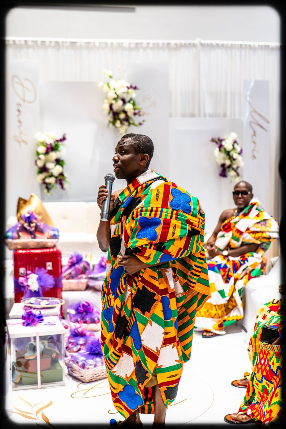 Dancers in vibrant African kente cloth perform energetic dance moves at a colorful celebration event.