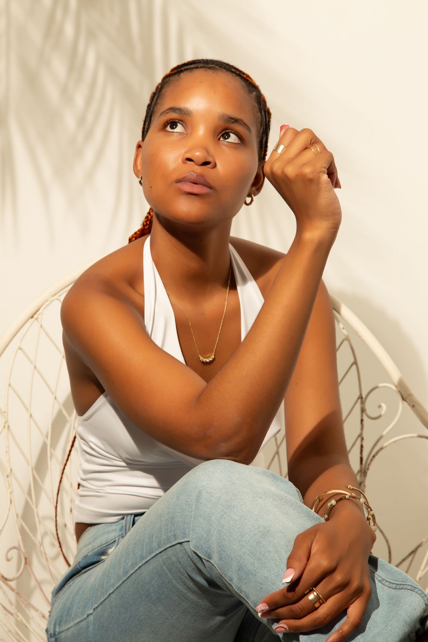Person in gray tank top and jeans poses thoughtfully against white background in artistic portrait series.
