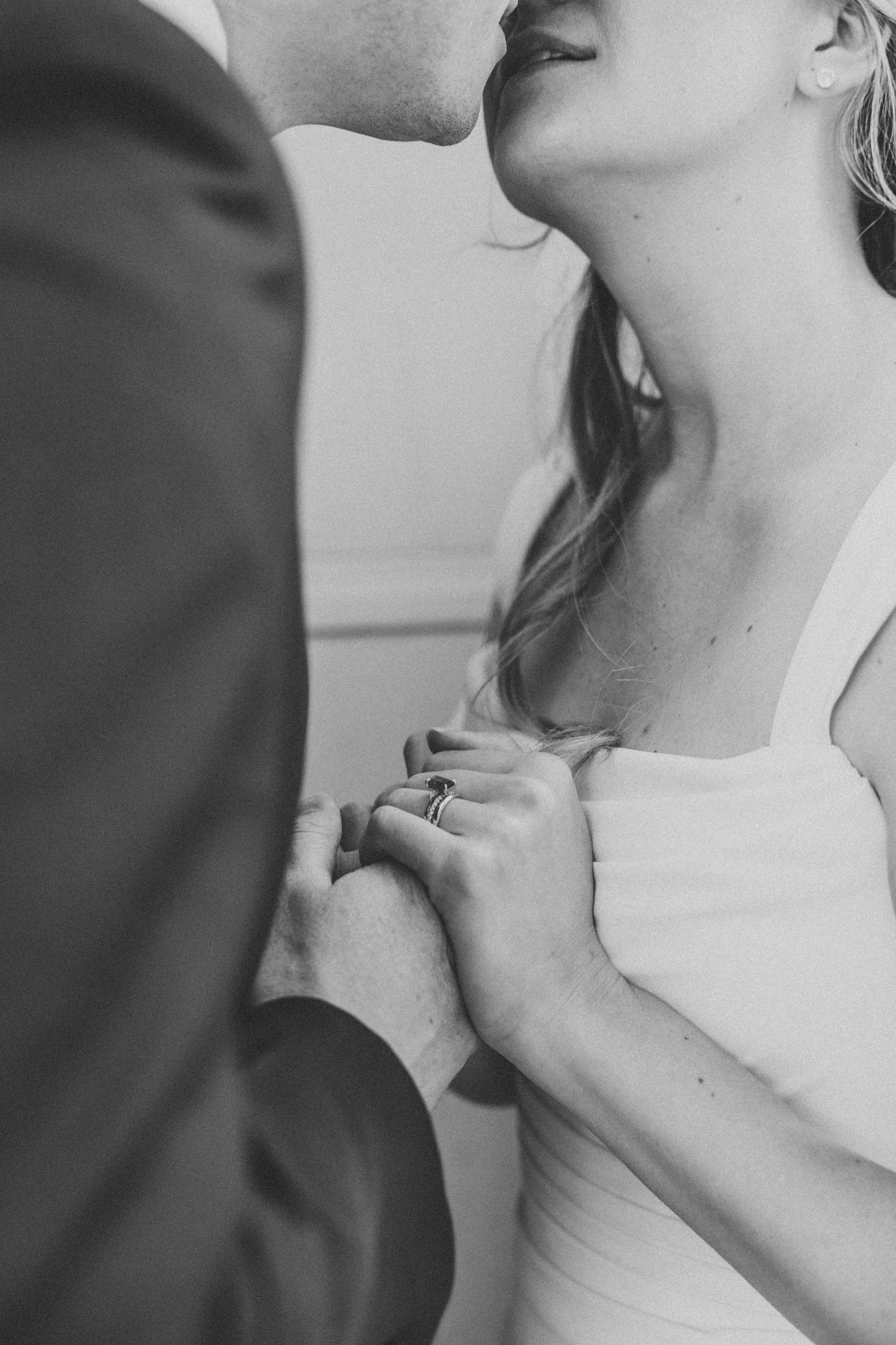 Close-up black and white photo of a romantic couple sharing an intimate moment in wedding attire.