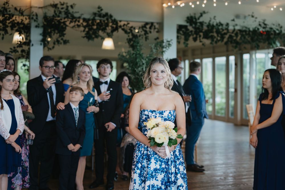 Wedding guests gather in an elegant venue decorated with string lights and greenery for an evening celebration.