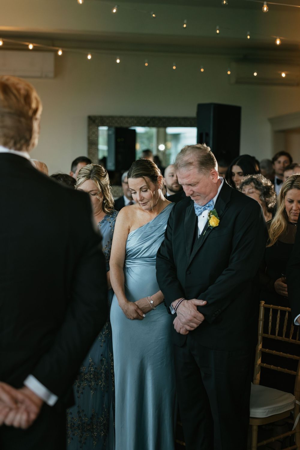 Emotional moment during a wedding ceremony as guests watch a couple embrace in a dimly lit reception venue.
