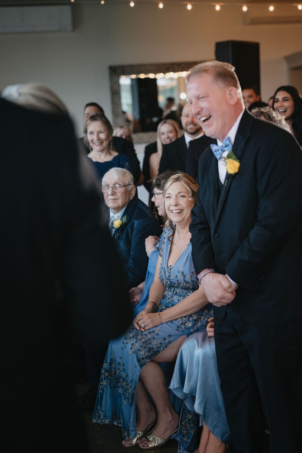 Joyful moments captured at a wedding reception showing guests laughing and enjoying festivities in blue formal attire.