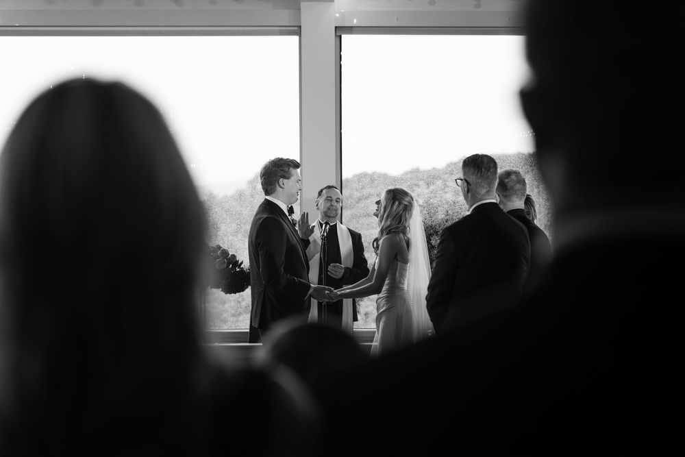 Silhouettes of people raising hands in a dark room with a bright window in the background.