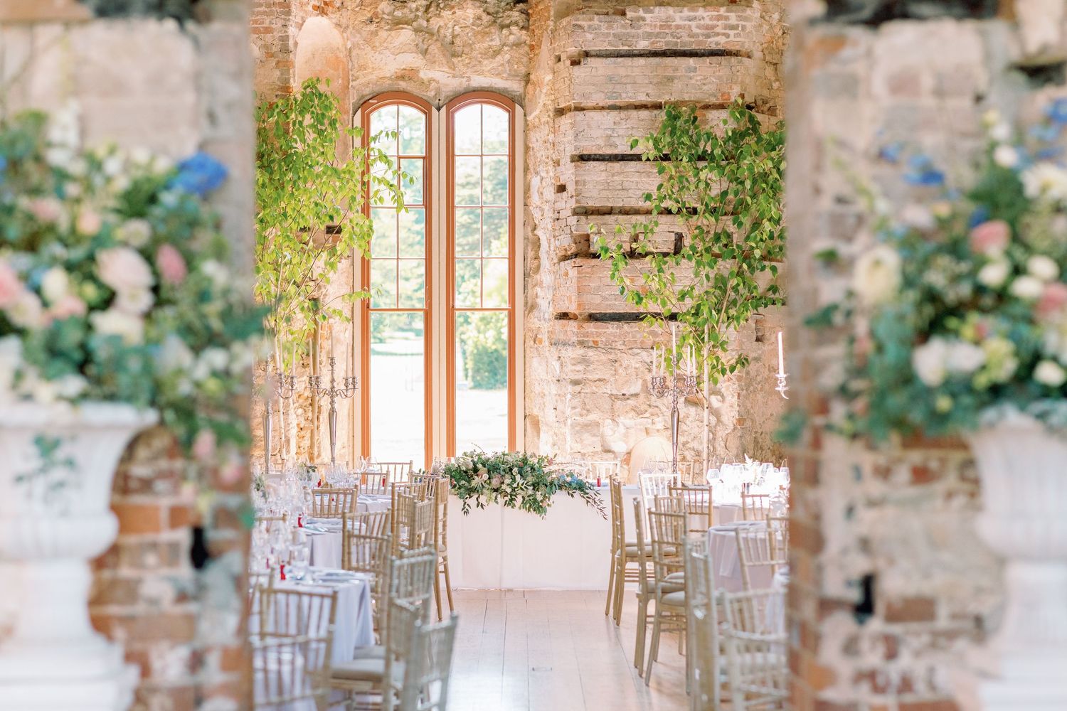 Elegant wedding venue with rustic stone walls, white floral arrangements, and wooden doors creating a romantic ambiance.