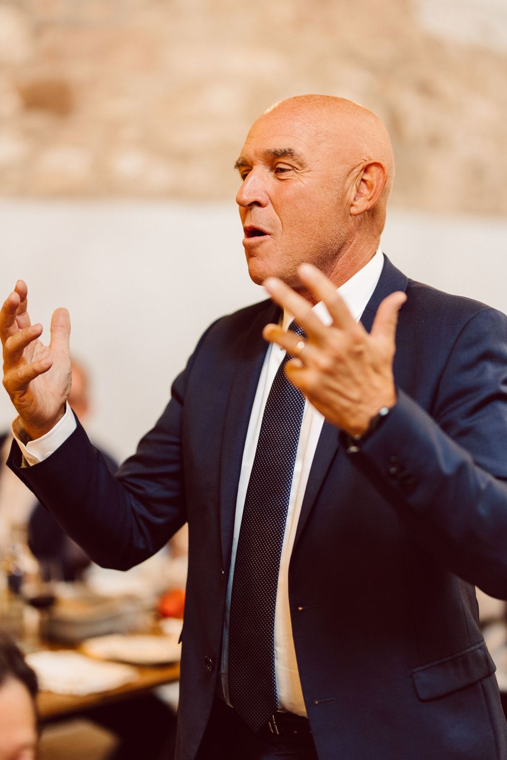 A sequence of photos showing a person in a dark suit gesturing expressively with their hands while speaking.