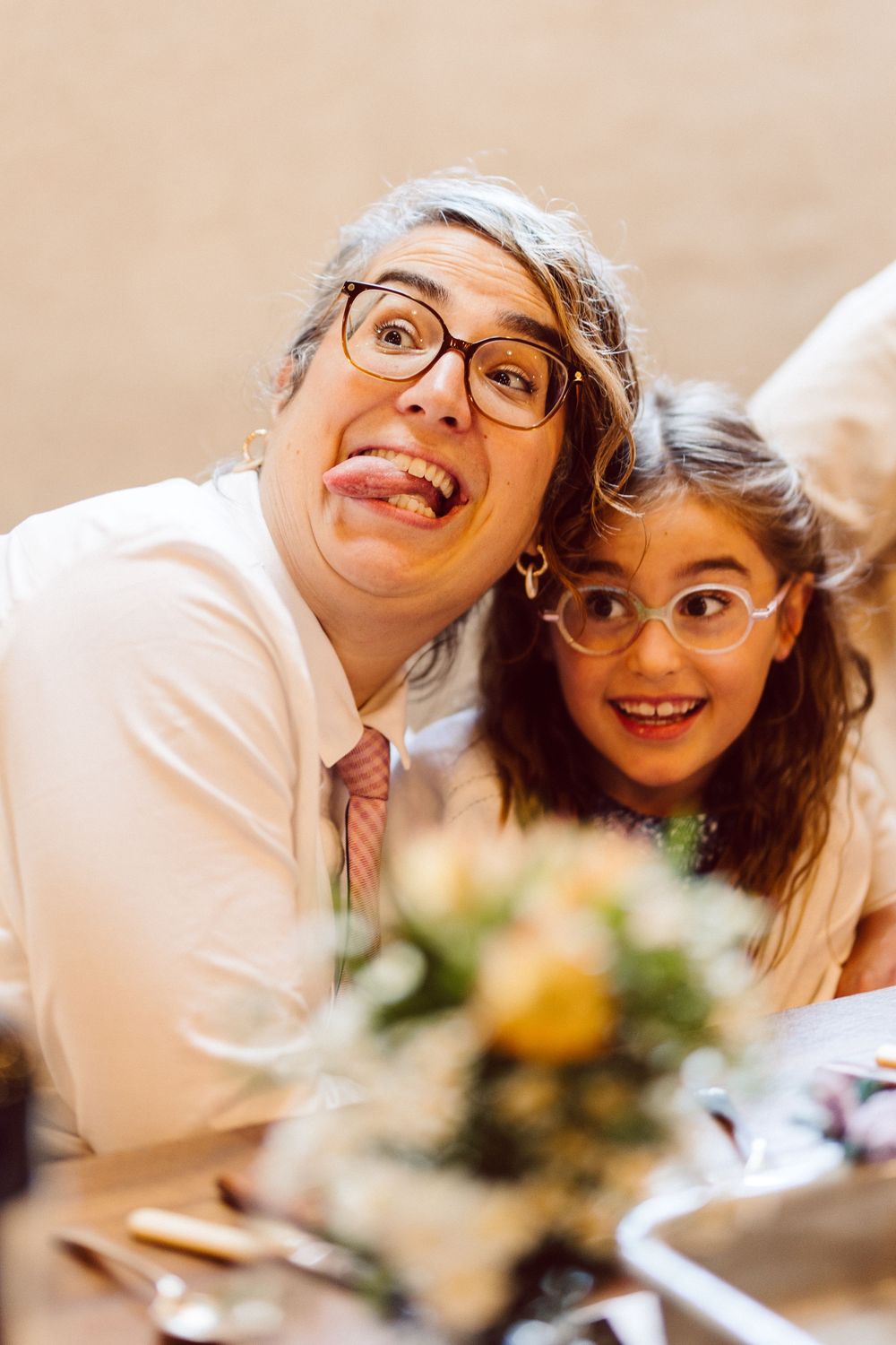 A happy couple wearing glasses lean in close together while smiling and enjoying a romantic moment.