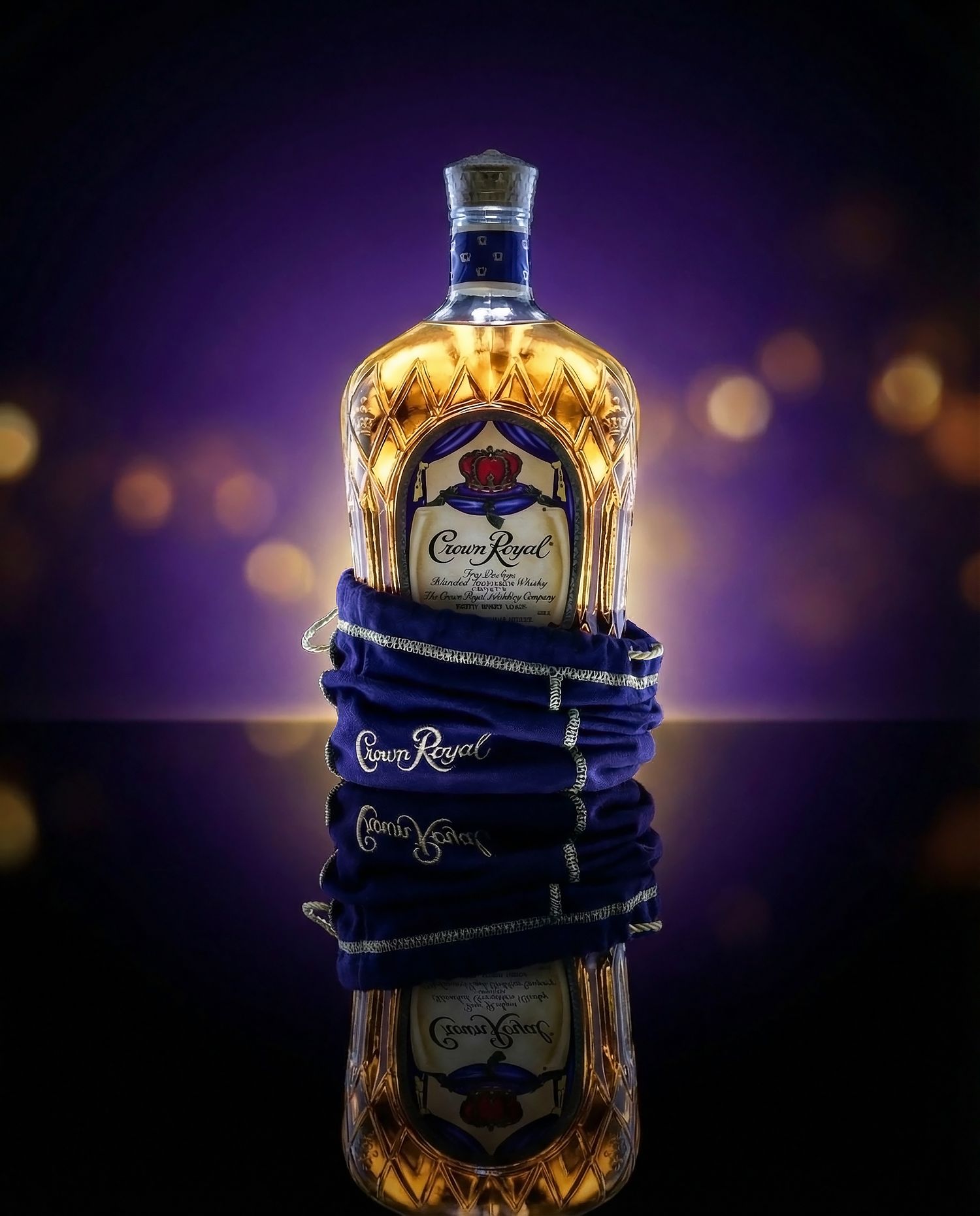 Crown Royal whiskey bottle wrapped in dark blue fabric displayed against a purple background with bokeh lights.