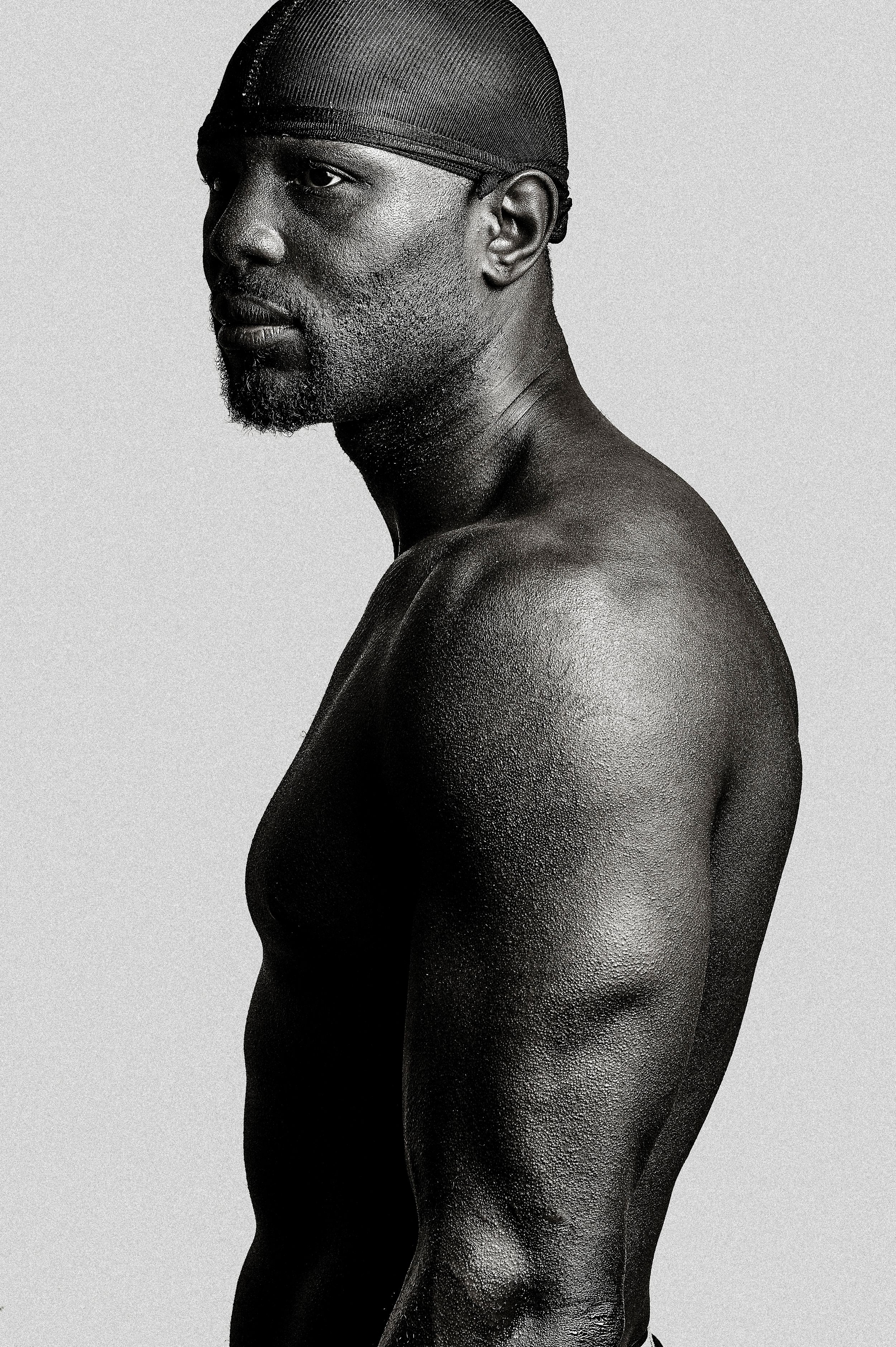 Black and white profile portrait of a muscular shirtless man wearing a du-rag, showcasing athletic physique.