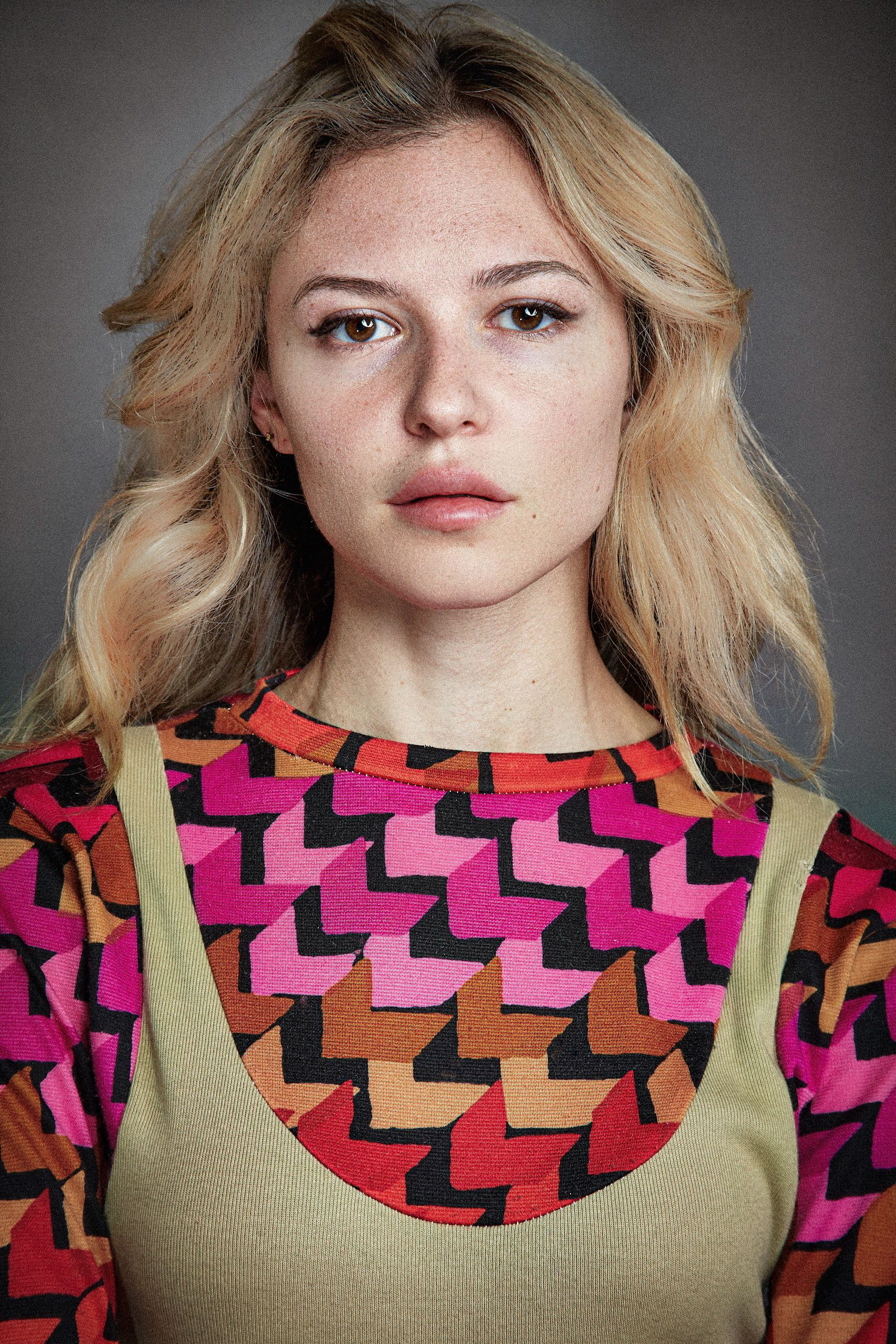 A series of portrait shots showing a model wearing a colorful geometric patterned top against a gray background.