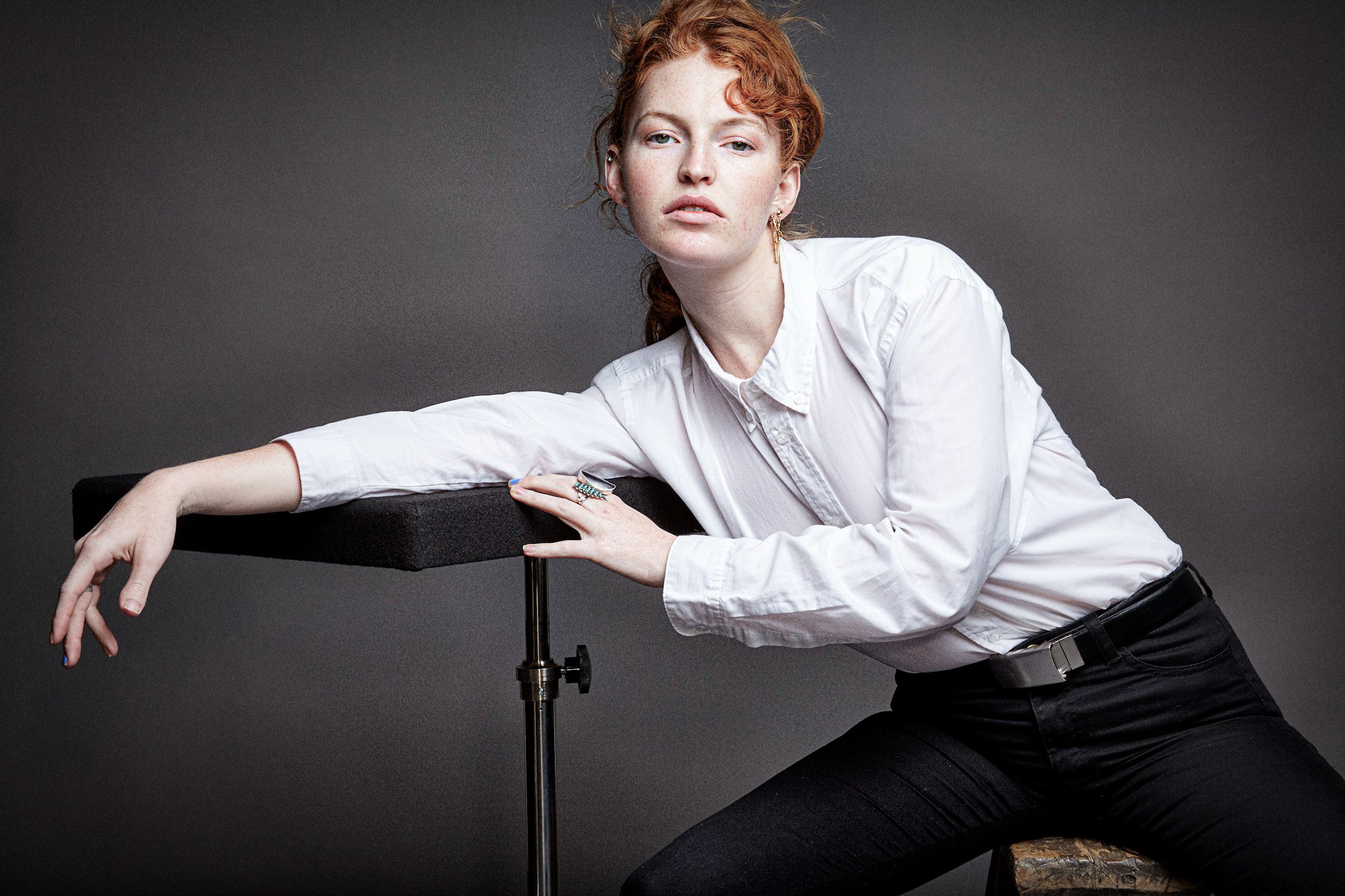 A dramatic black and white photo series showing someone in a white shirt posing against a dark background.