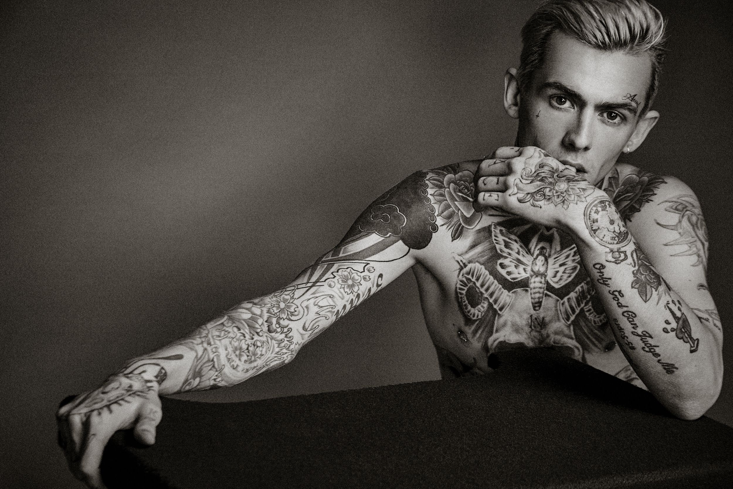A black and white photo series showing hands with tattoos in different poses and gestures.