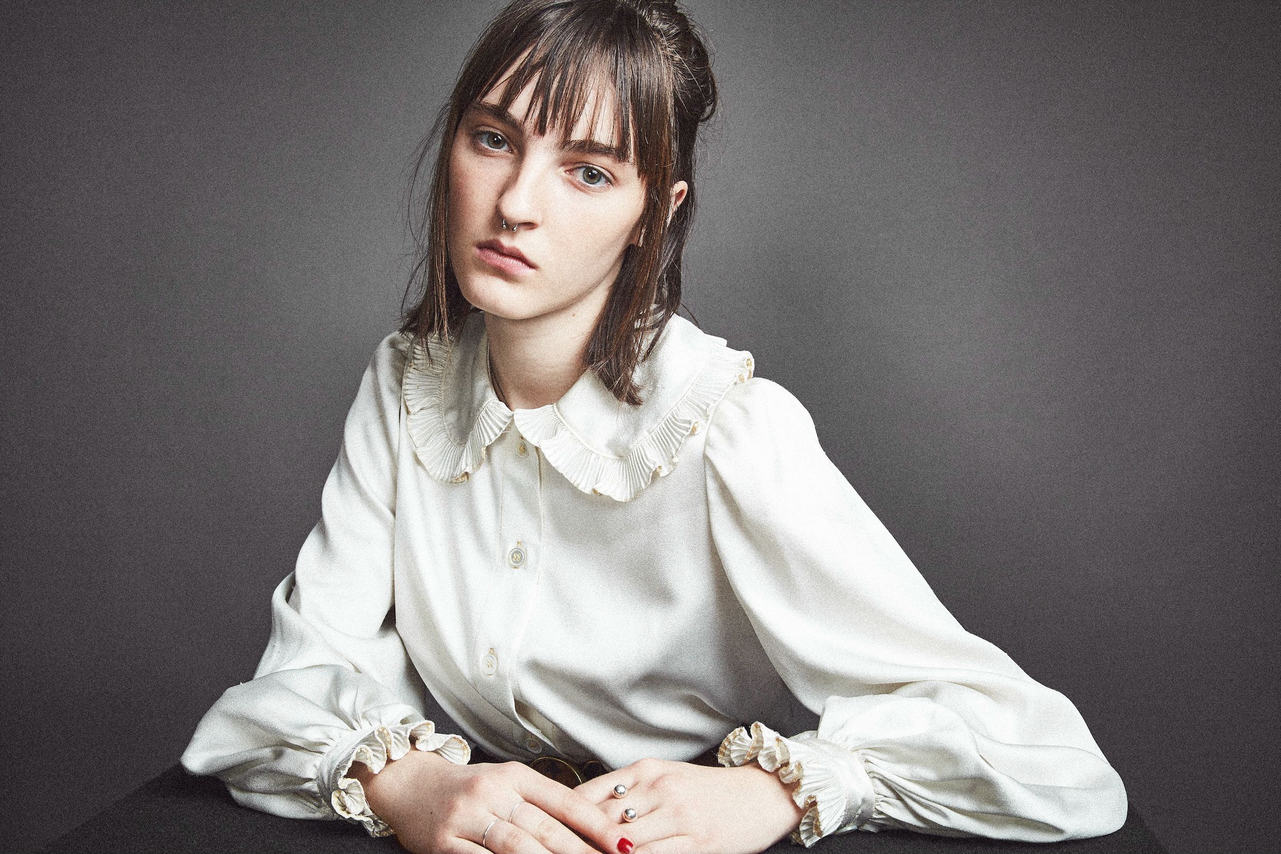 A series of black and white portraits showing a person in a white button-up shirt against a dark background.