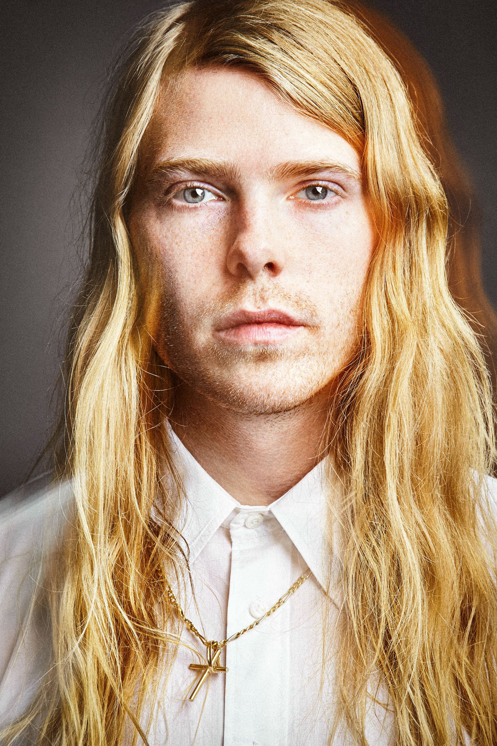 A series of portrait photos showing a person with long blonde hair wearing a white collared shirt against a dark background.