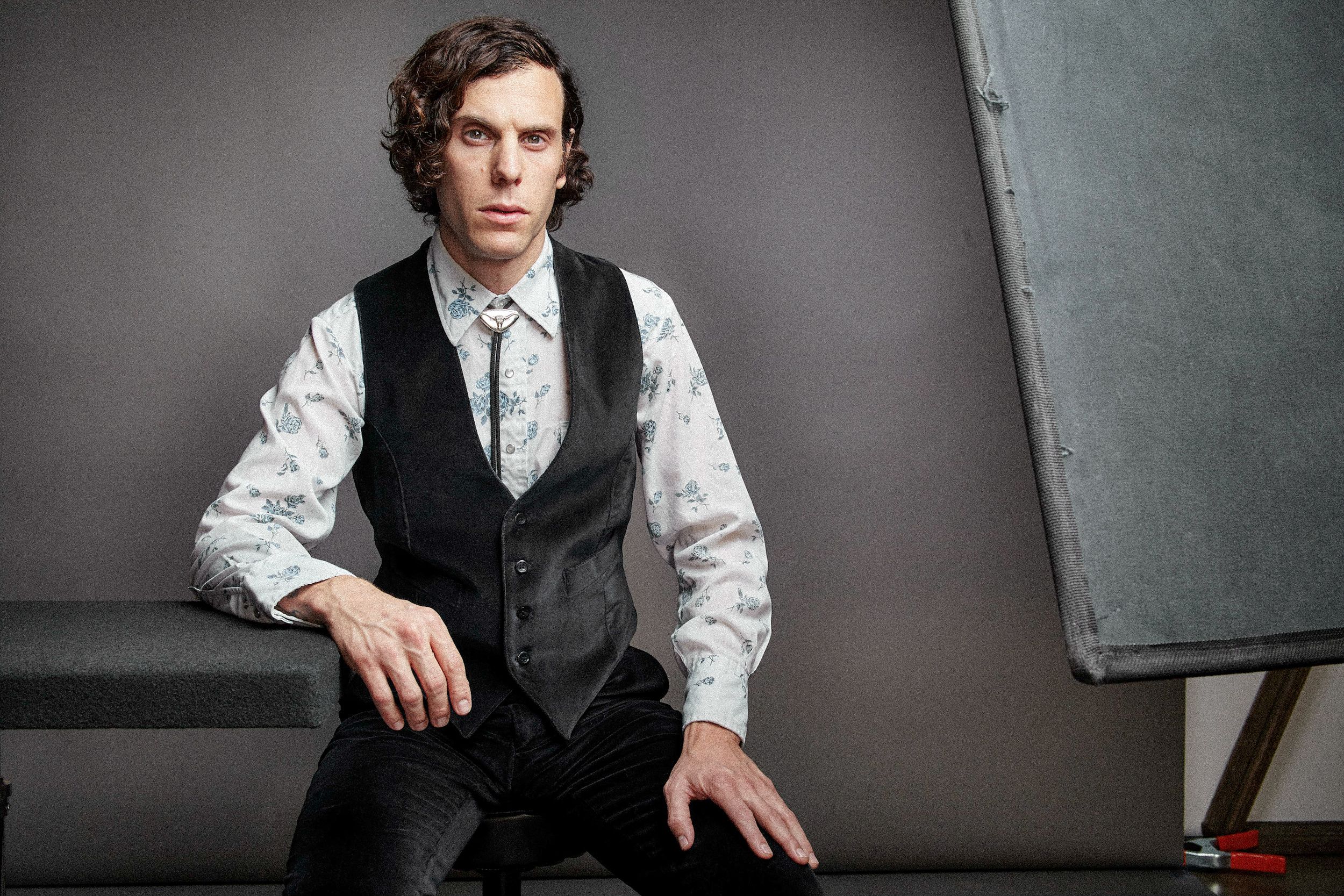 A series of black and white photos showing someone in formal attire with a vest and white shirt against a dark background.