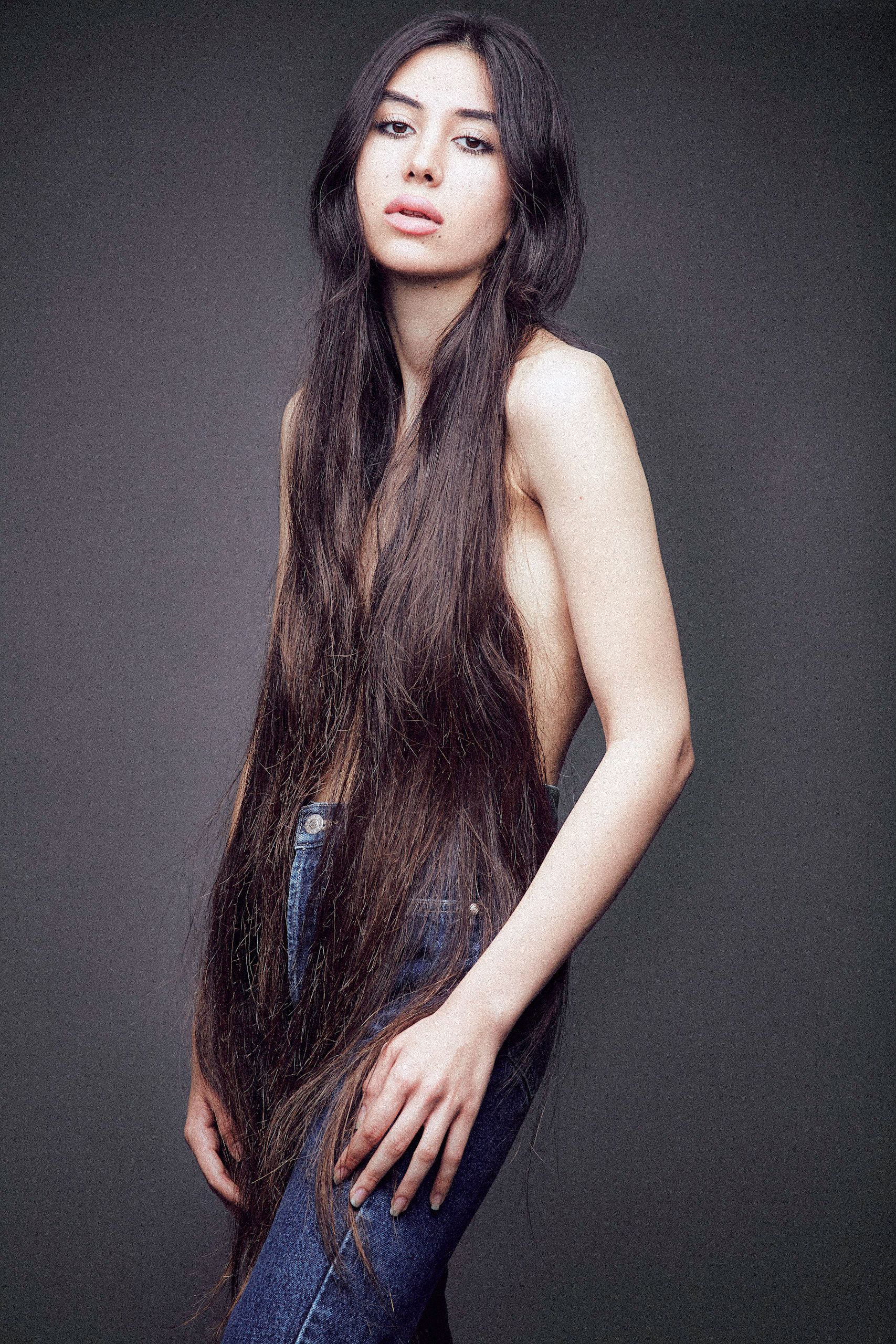 Studio portrait series featuring long dark hair against dramatic gray background in elegant poses.