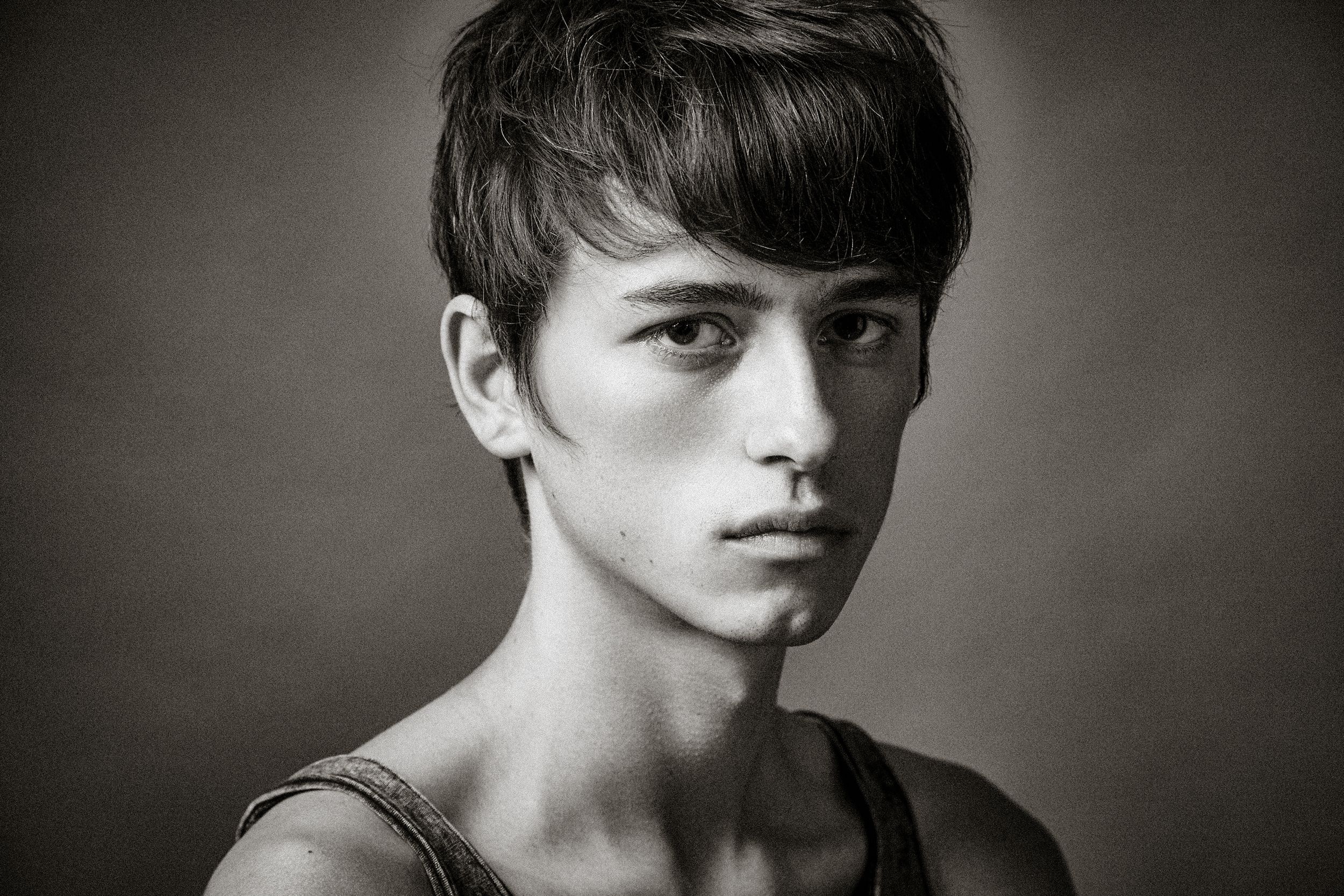 A dramatic black and white portrait series showing close-up facial expressions against a dark background.