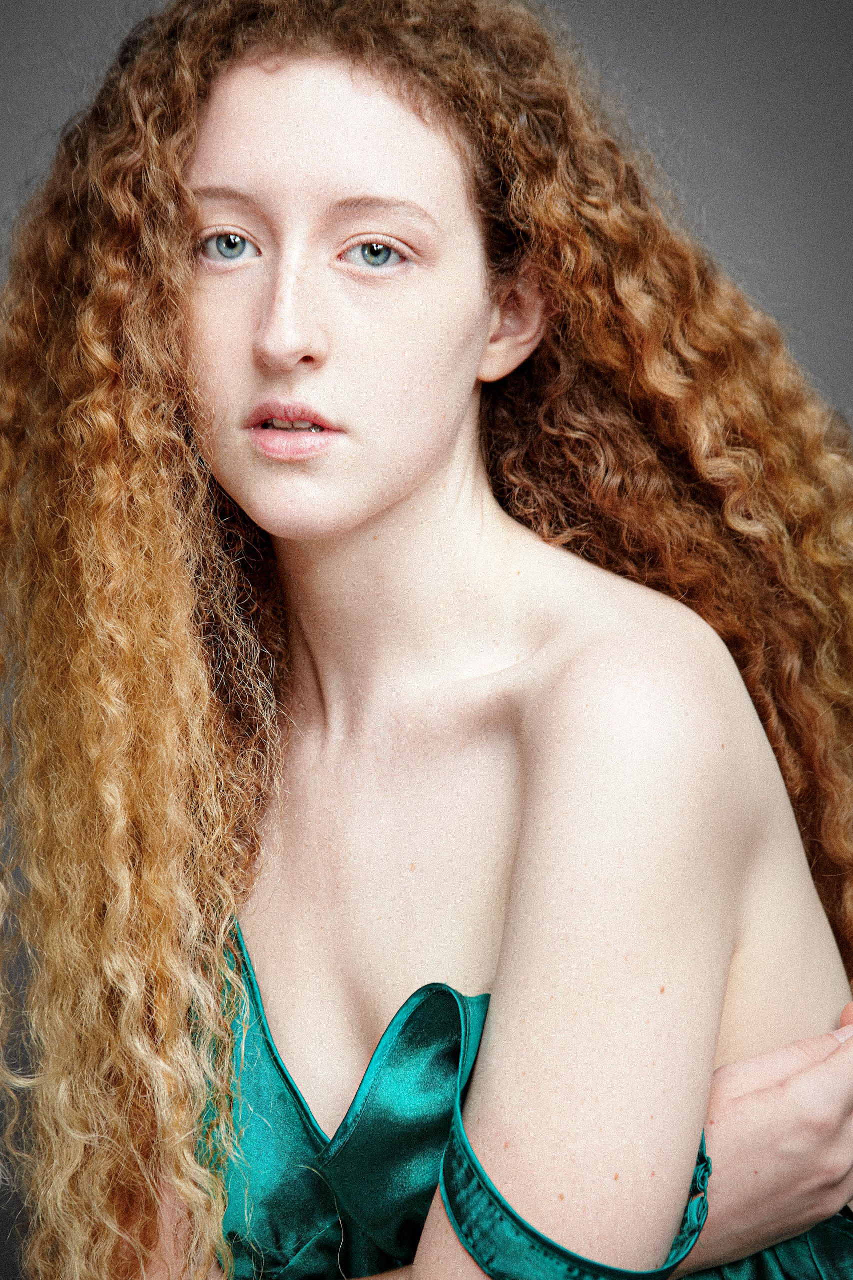 Portrait series showing long curly red hair and emerald green dress against grey background.