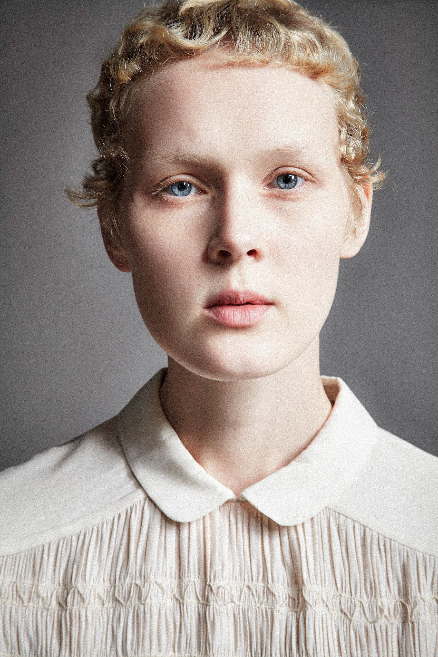 Portrait series showing different angles of a person with pale skin and blonde curly hair wearing a white collared shirt.