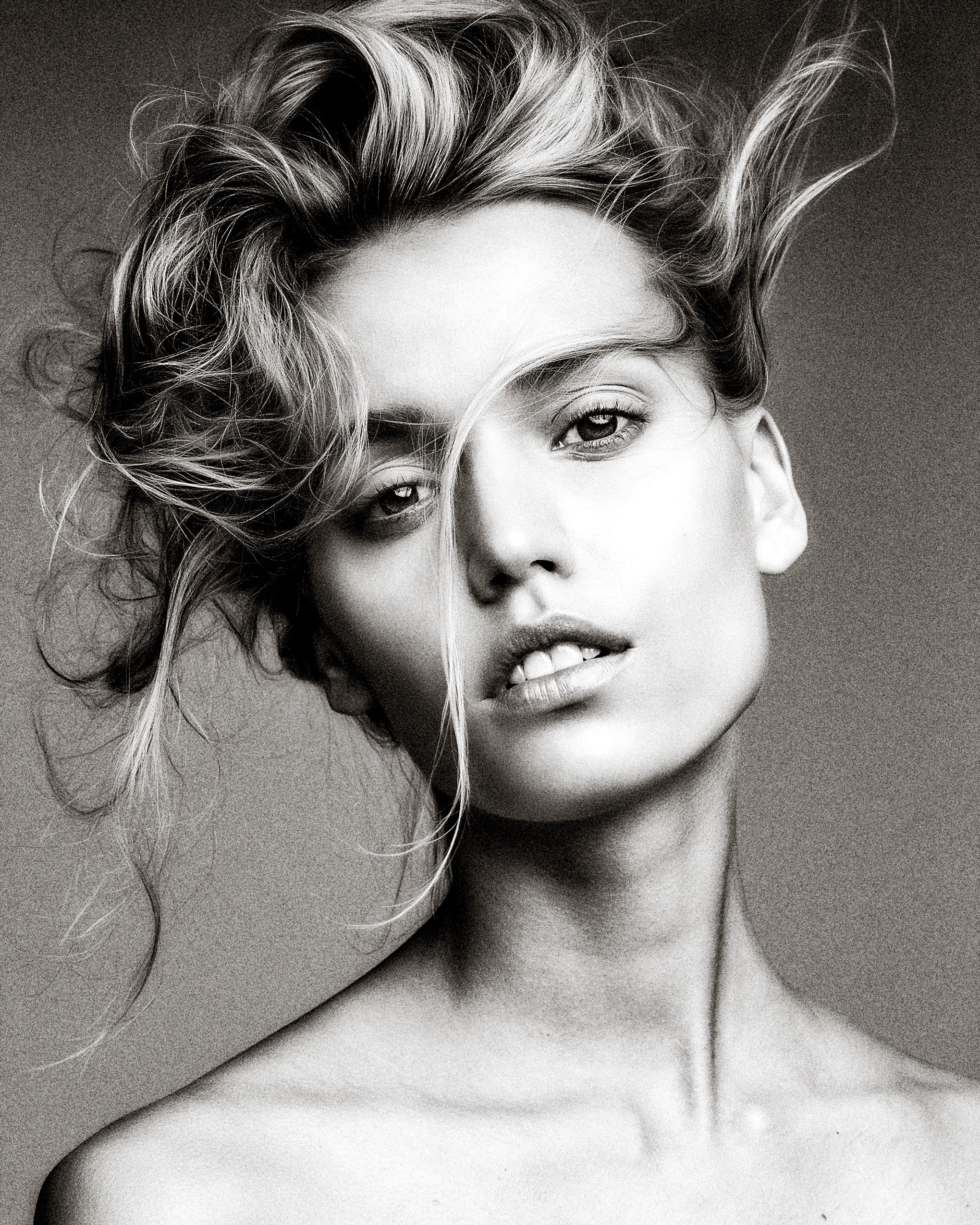 Artistic black and white fashion portrait series showing dynamic poses with windswept hair against neutral background.