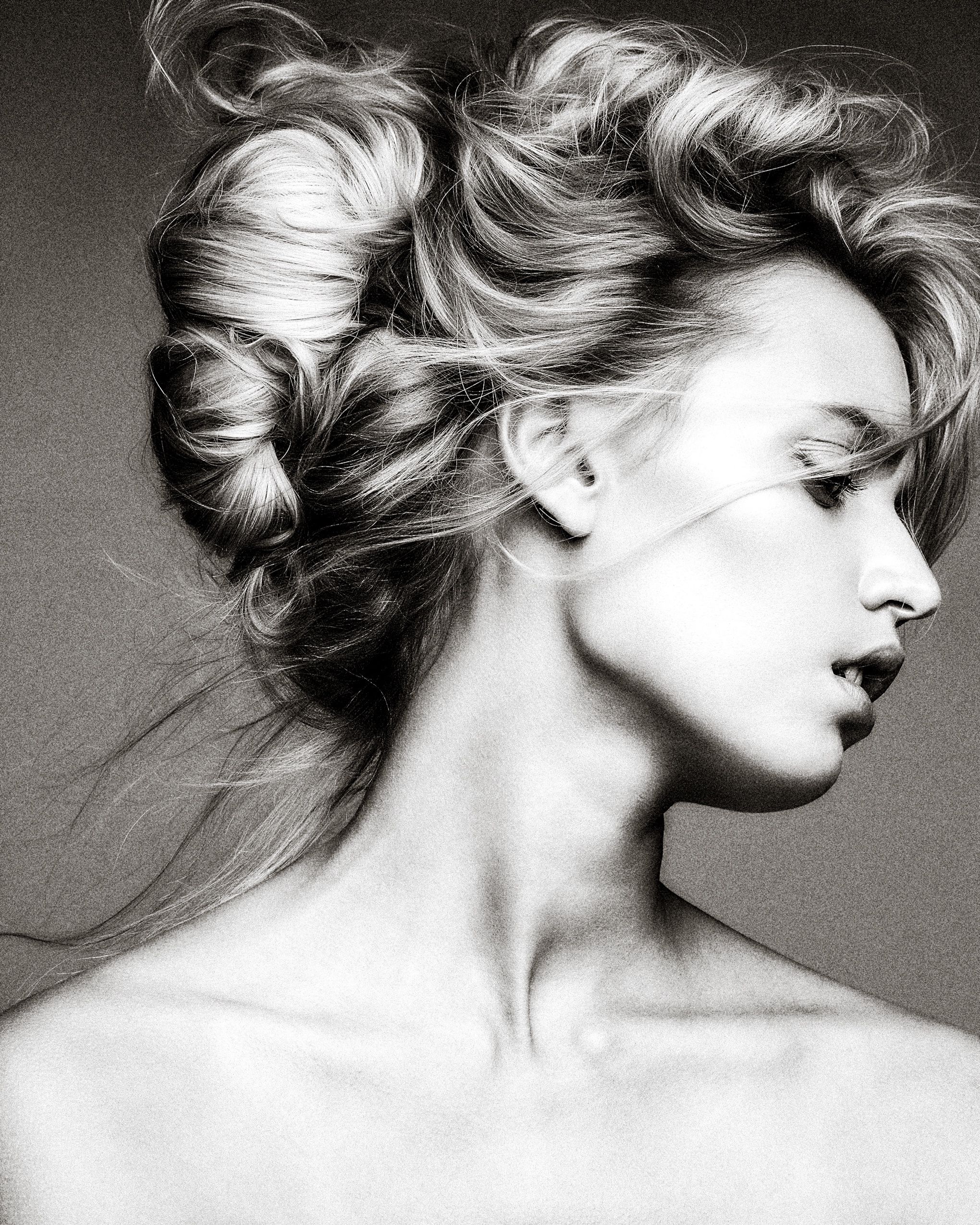 Artistic black and white profile portraits showing dramatic movement and styling of blonde hair against neutral background.