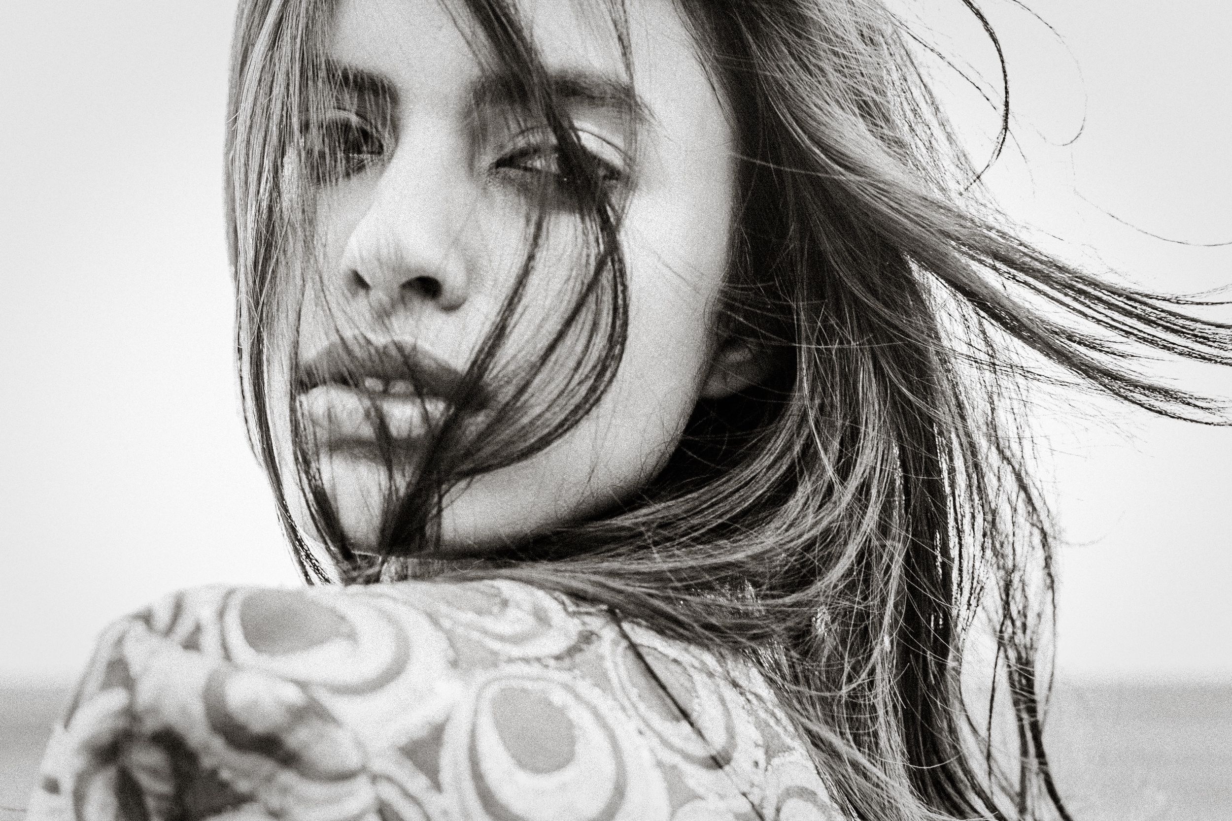 Black and white fashion photo series showing dramatic wind-blown hair movement against white background.