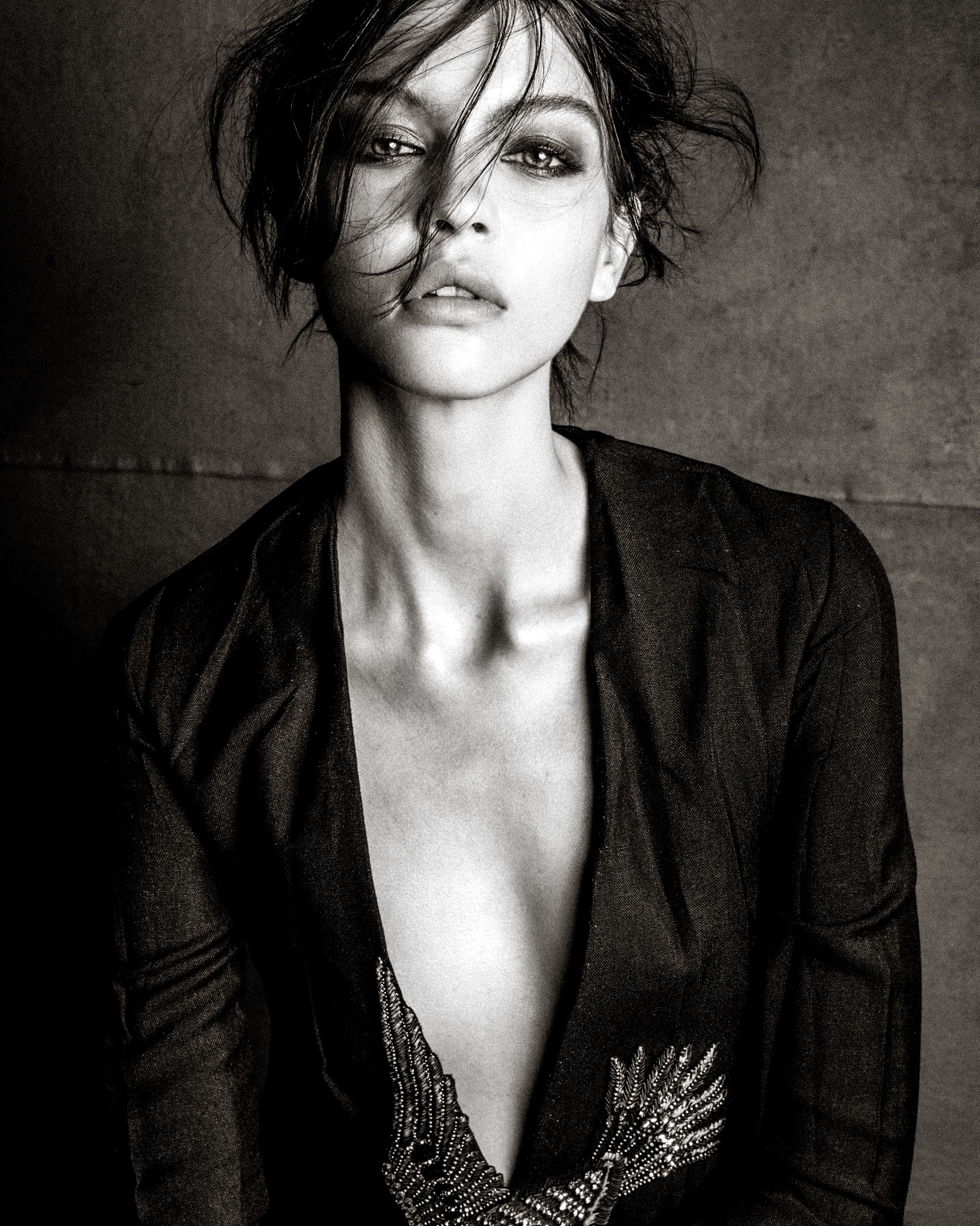 Dramatic black and white fashion portrait series showing moody poses in a dark blazer with embellished neckline detail.