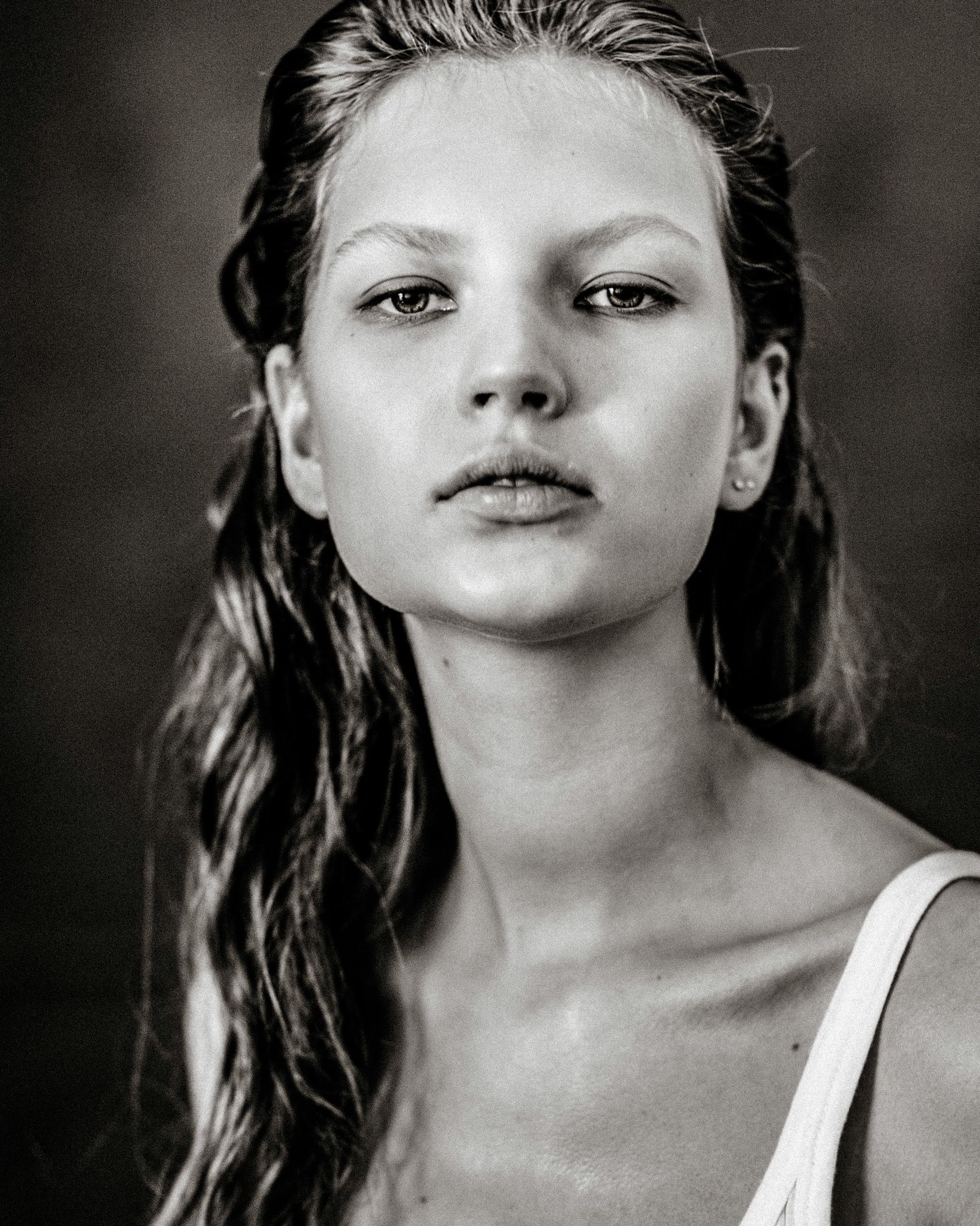 A series of black and white headshots showing a woman with wet hair and a white tank top in various poses.