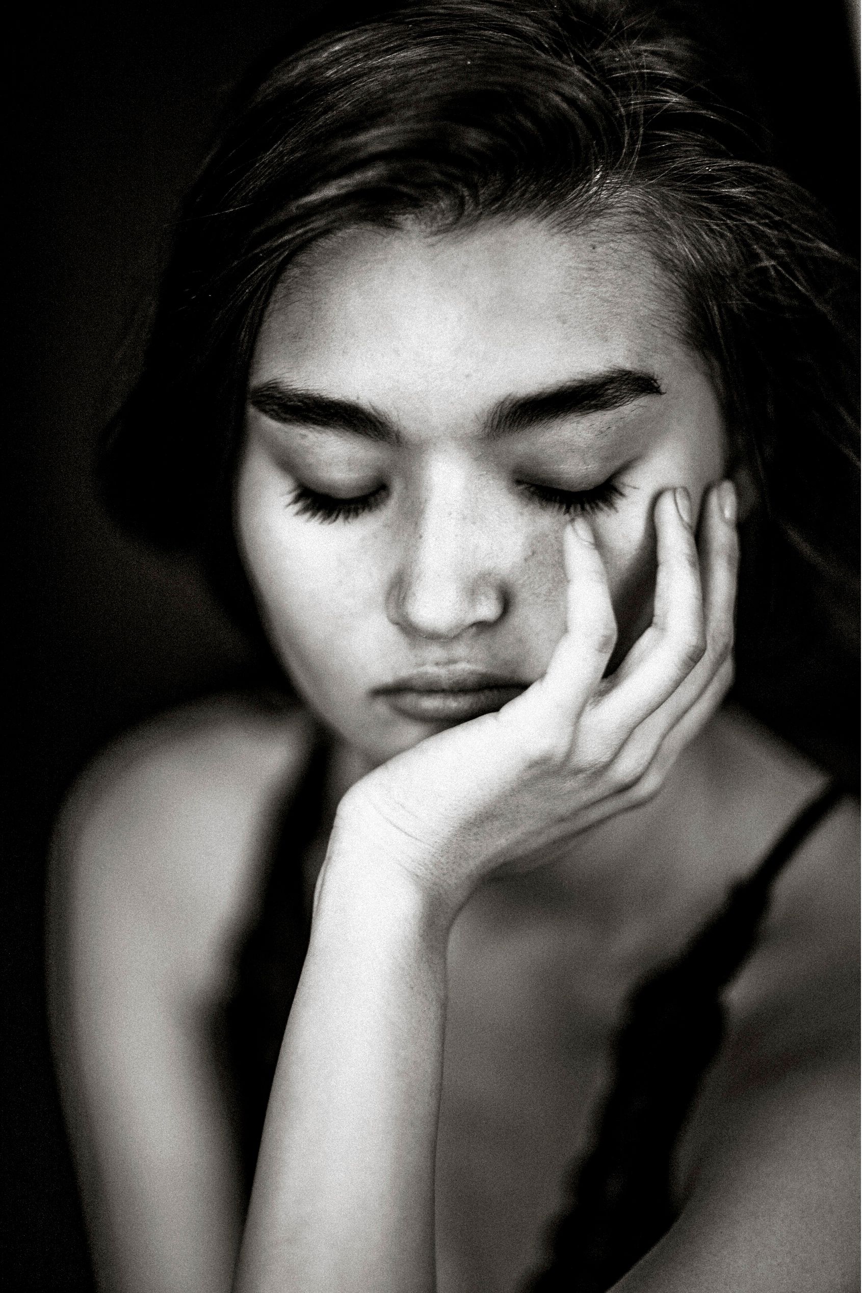 A series of black and white portraits showing a person with closed eyes and hand against face in contemplative poses.