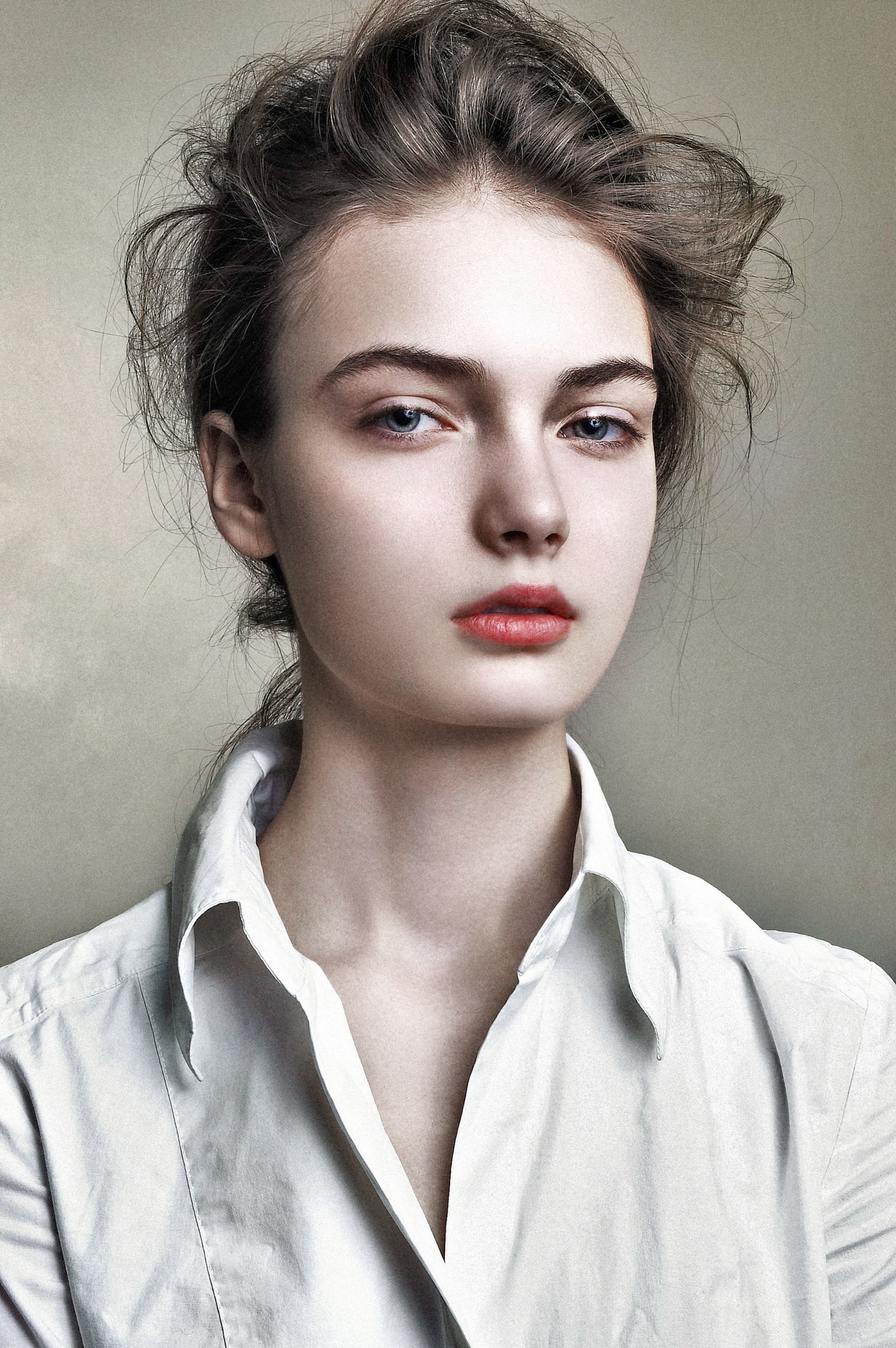 A portrait shot with dramatic lighting shows a person in a white button-down shirt wearing bold red lipstick.