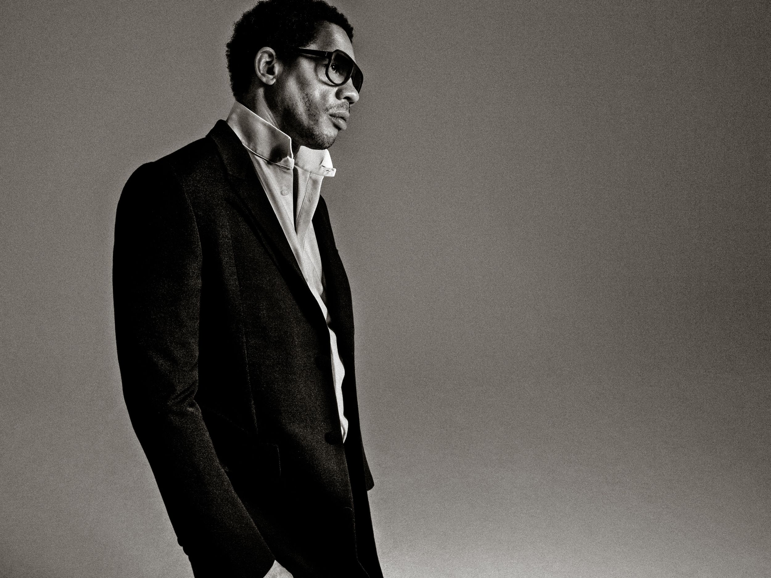 A black and white photo series showing a person in a suit posing against a plain background.