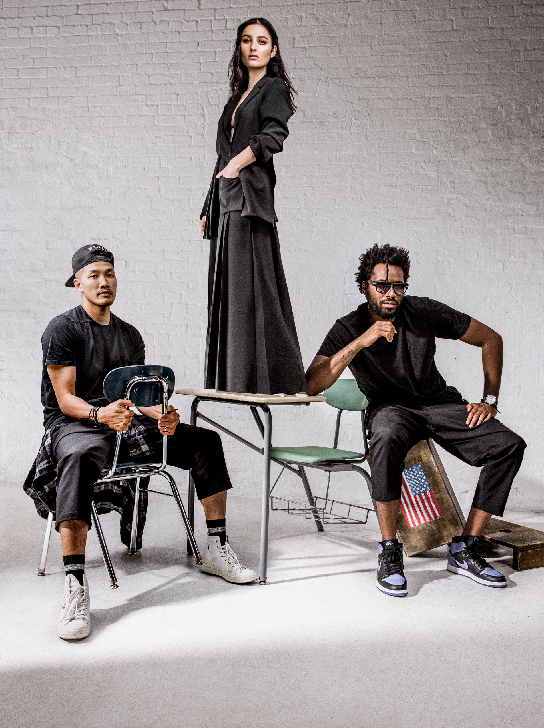 Five artistic black and white fashion photos showing people seated on chairs against a white brick wall wearing dark clothing.