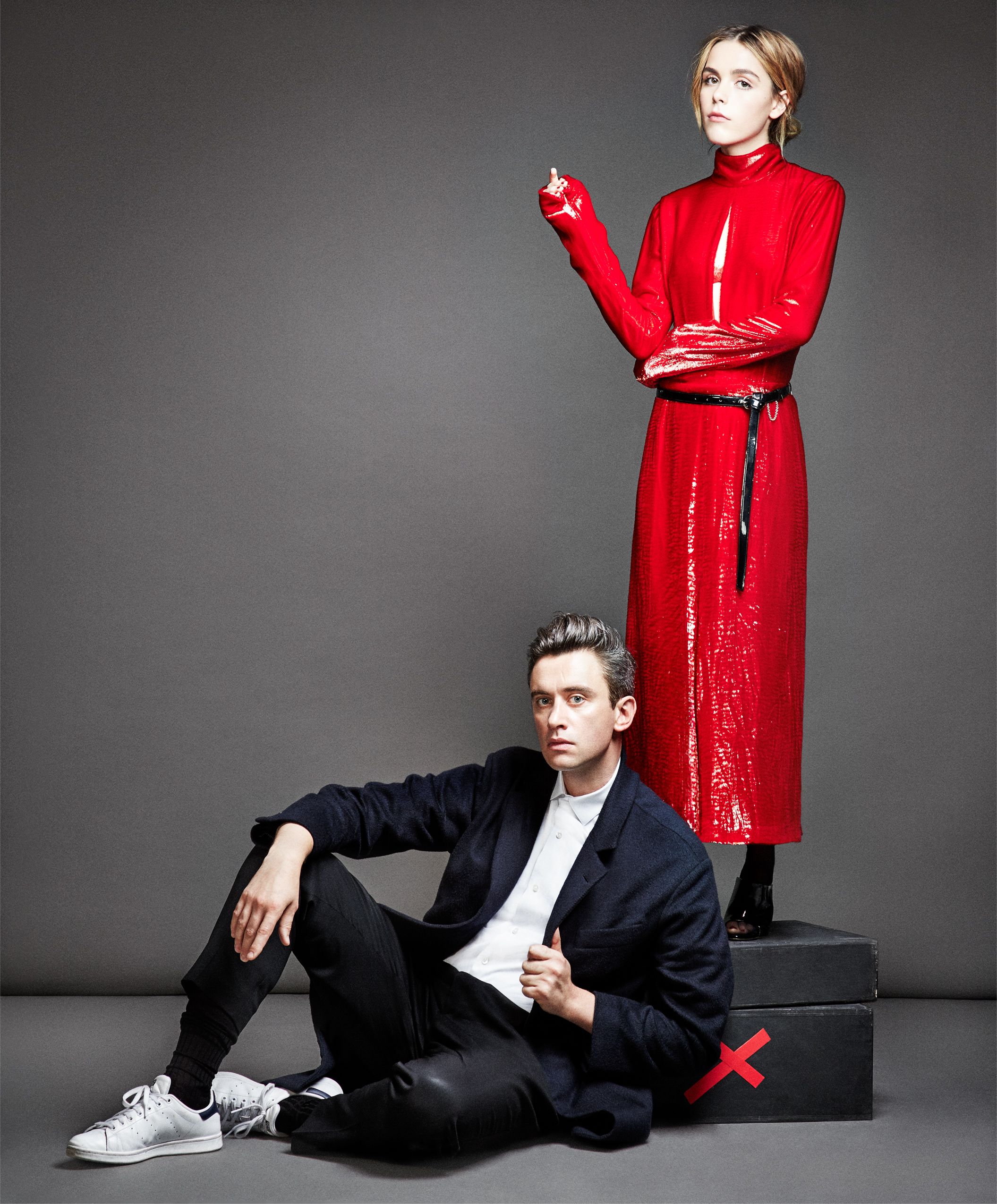 Fashion photo series showing a model in black suit and red coat against gray backdrop in various poses.