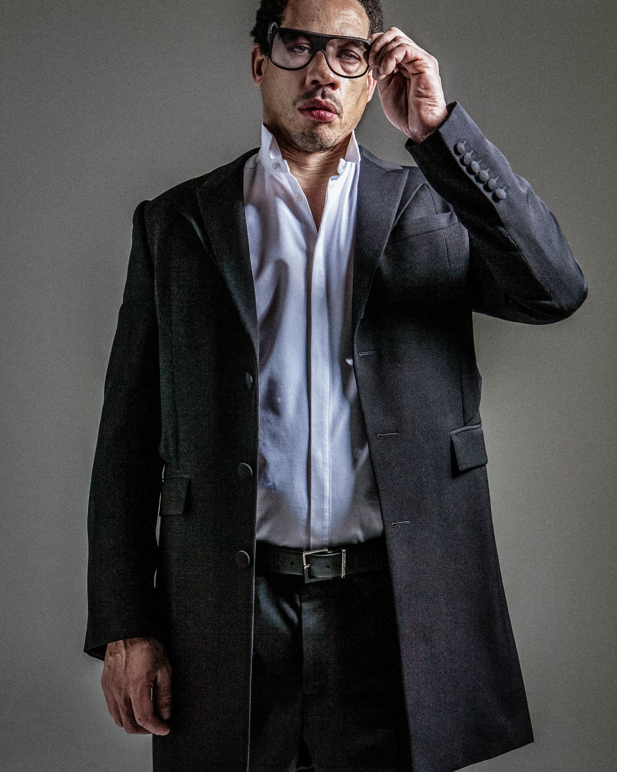 Studio portrait series showing a person in dark suit and glasses posing against gray background.
