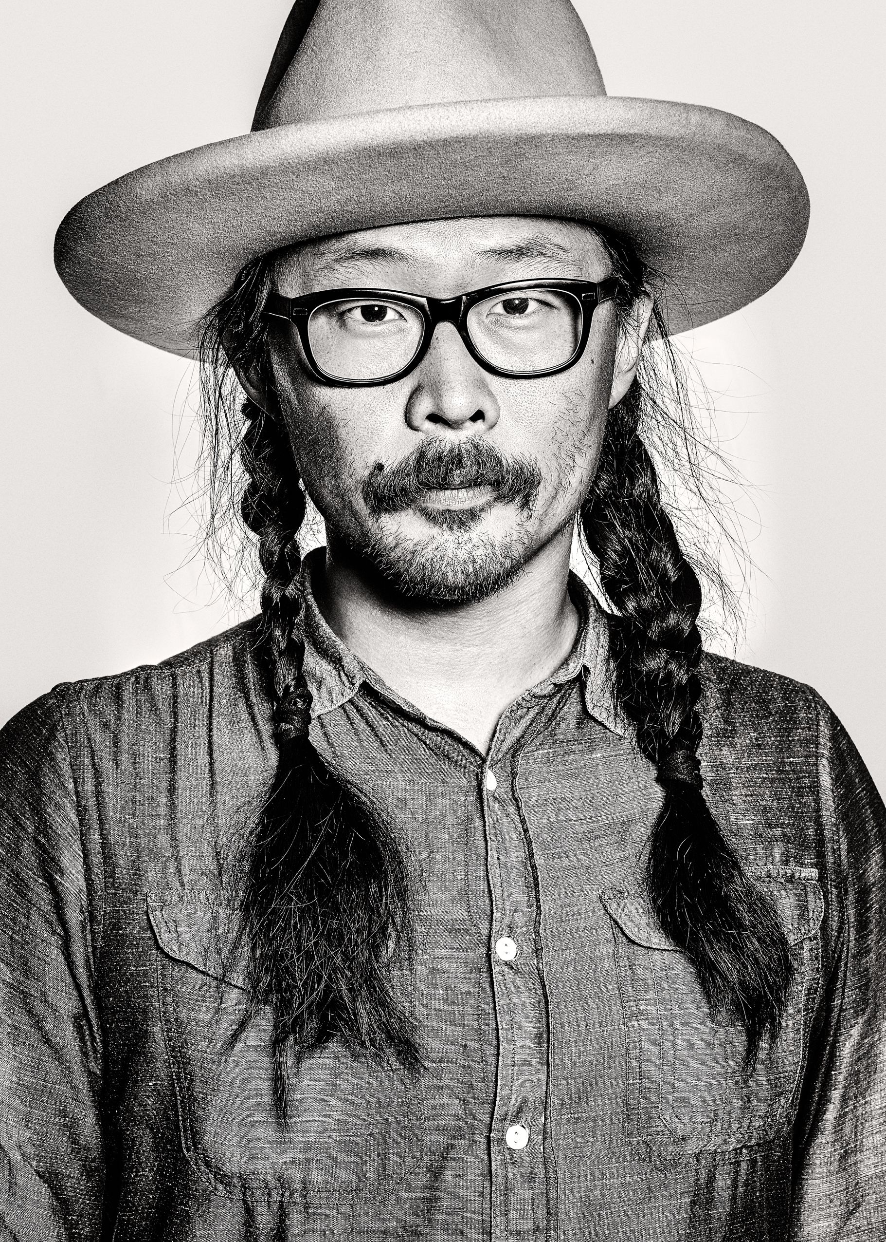 A series of four black and white portraits showing someone wearing a hat and glasses in different poses against a white background.