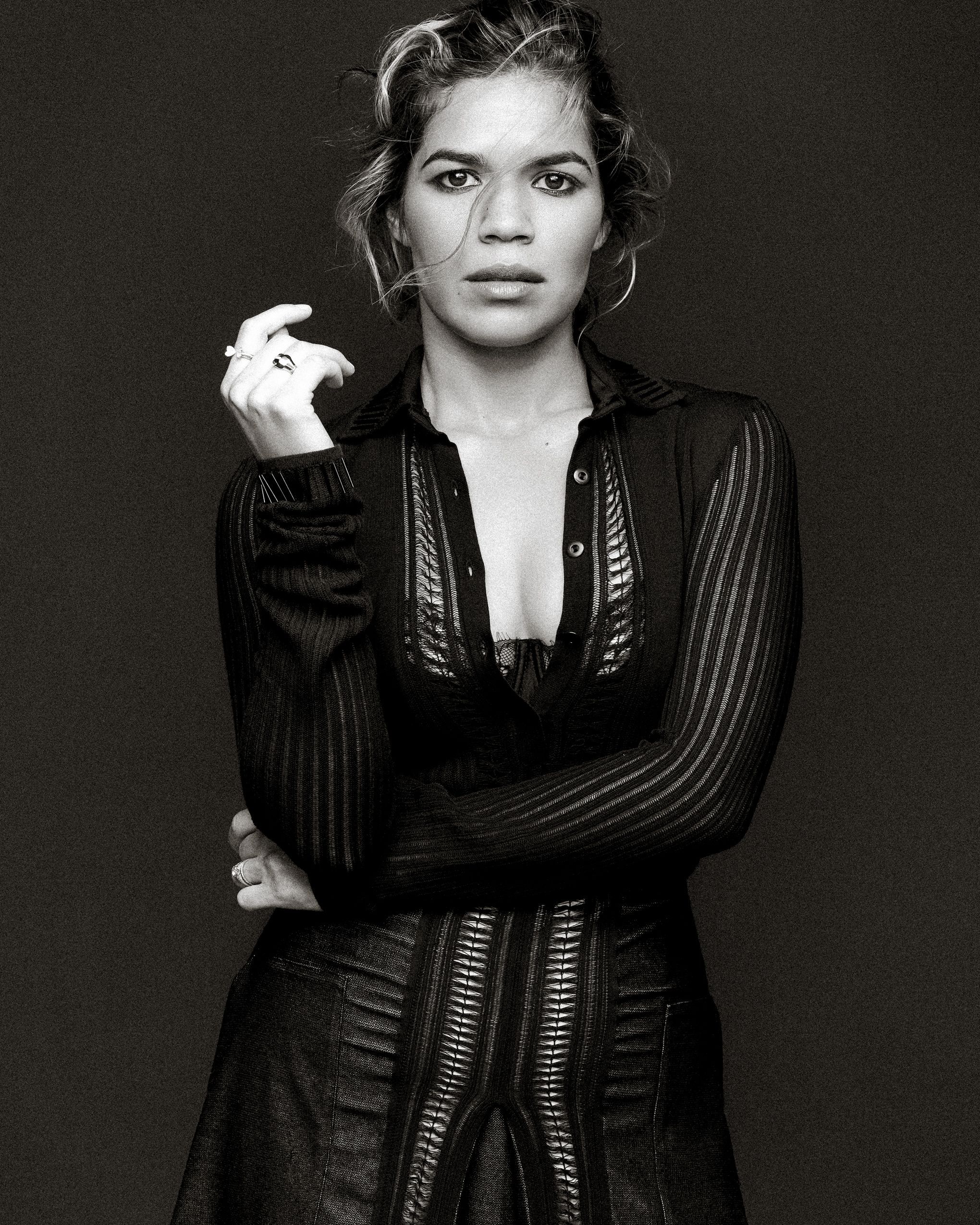 Black and white portrait of woman in sheer striped black dress against dark background.