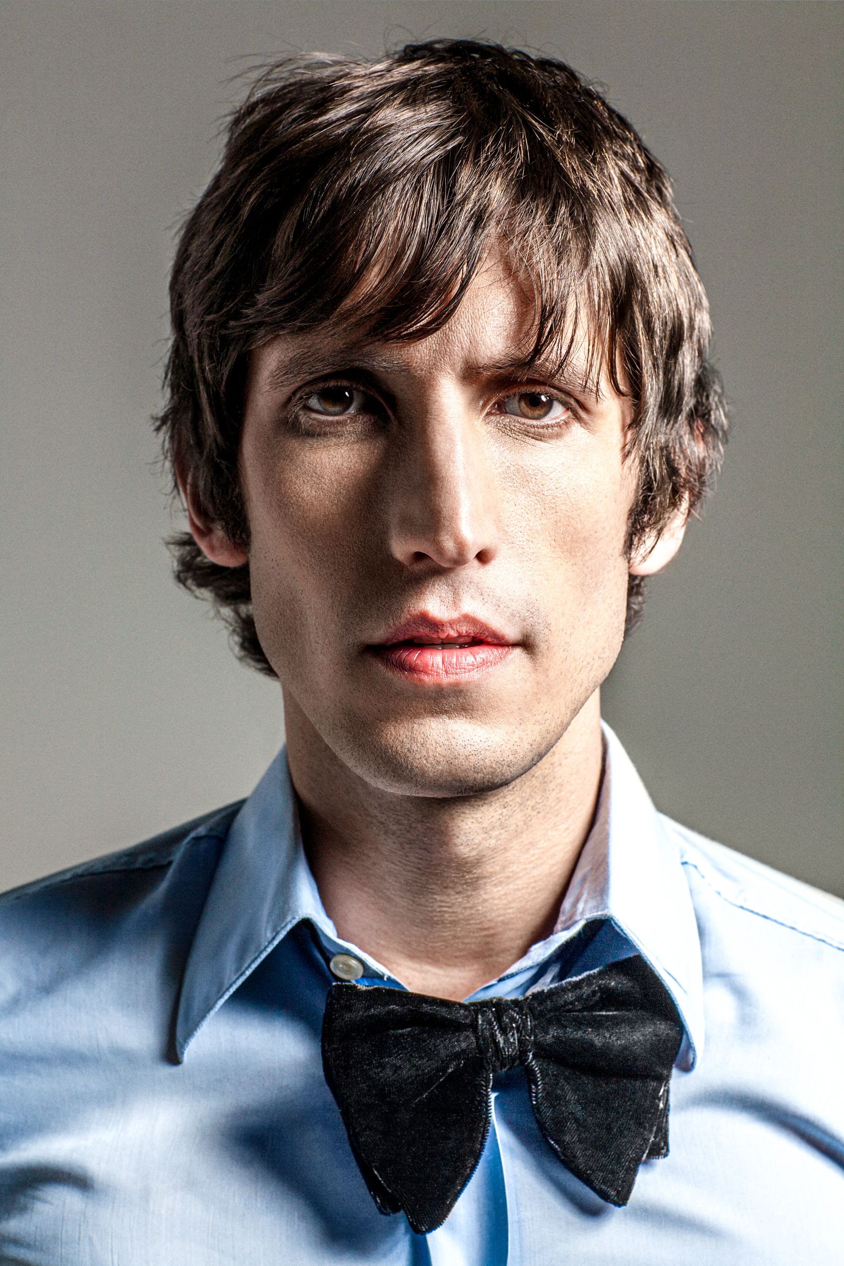 Four profile views of a person wearing a light blue dress shirt and black bow tie against a white background.