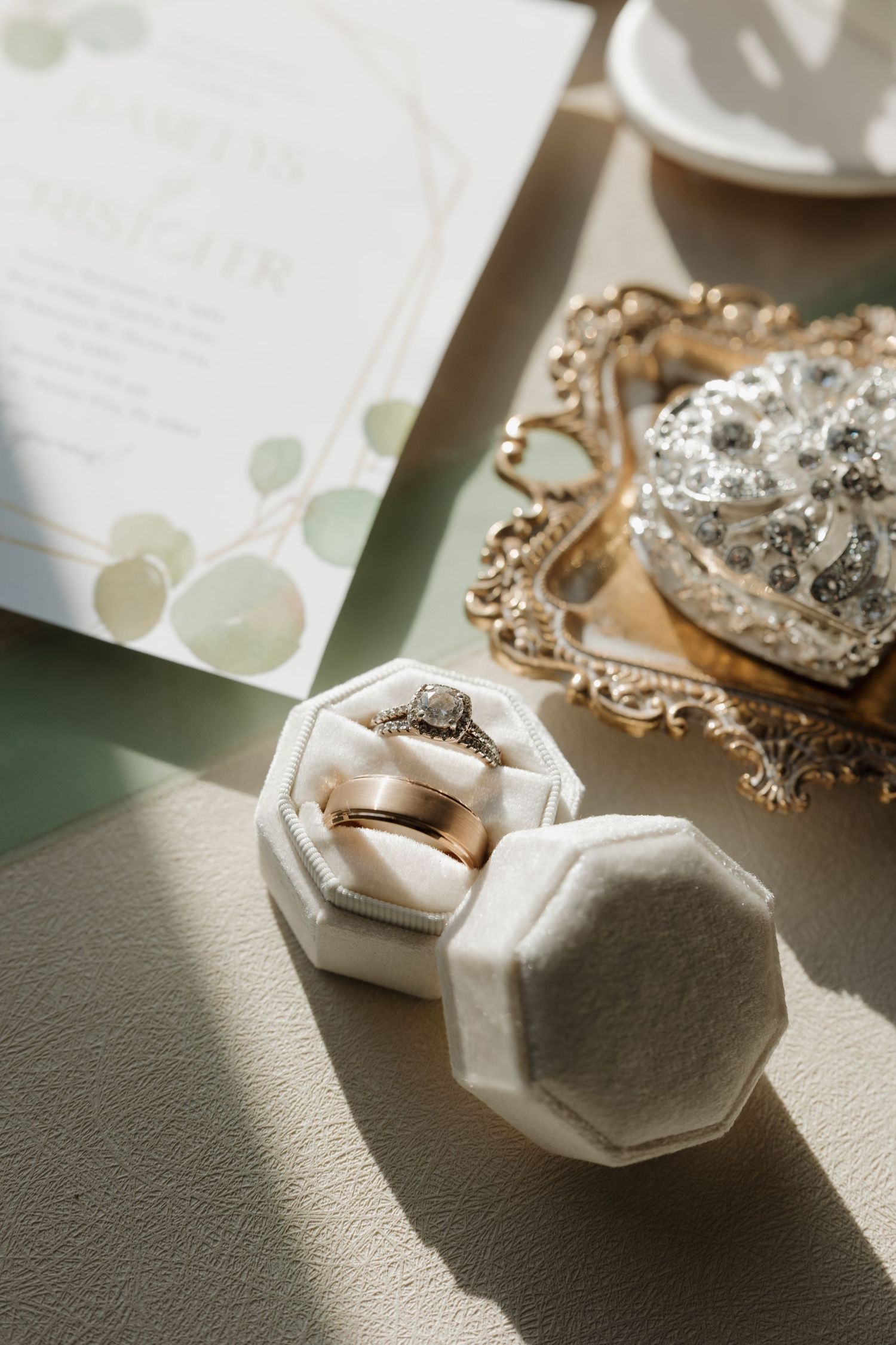 Wedding rings and jewelry displayed in elegant white hexagonal boxes casting soft shadows.