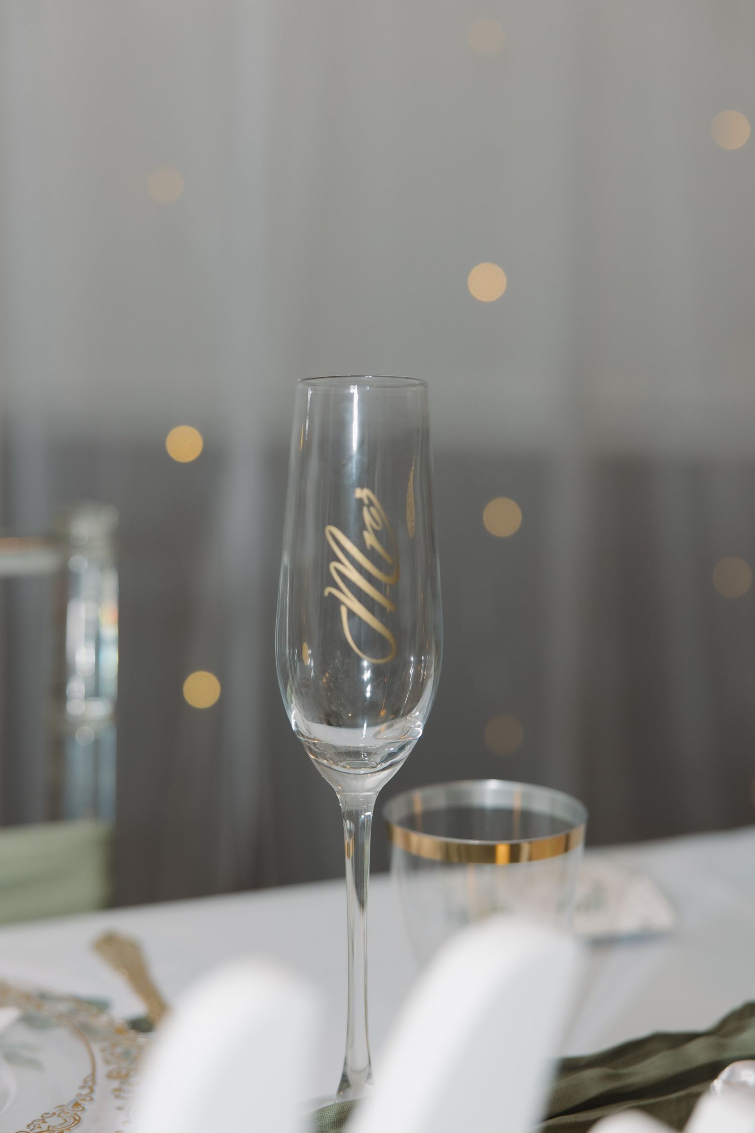 Elegant champagne glasses set on a white tablecloth with soft bokeh lights in the background.
