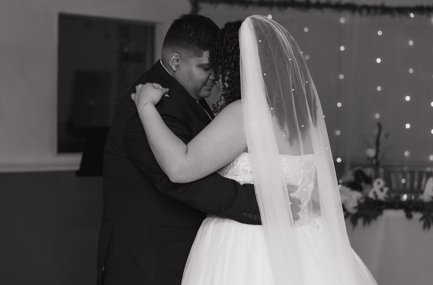 Romantic first dance sequence captured at a wedding reception with twinkling lights in the background.