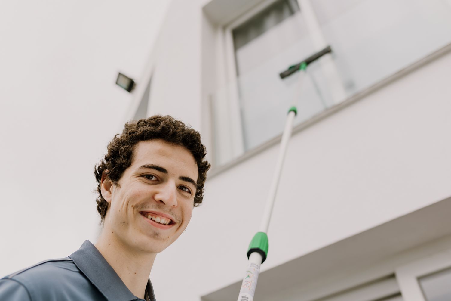Photo of Tom cleaning an high window crystals  with his long special stick.