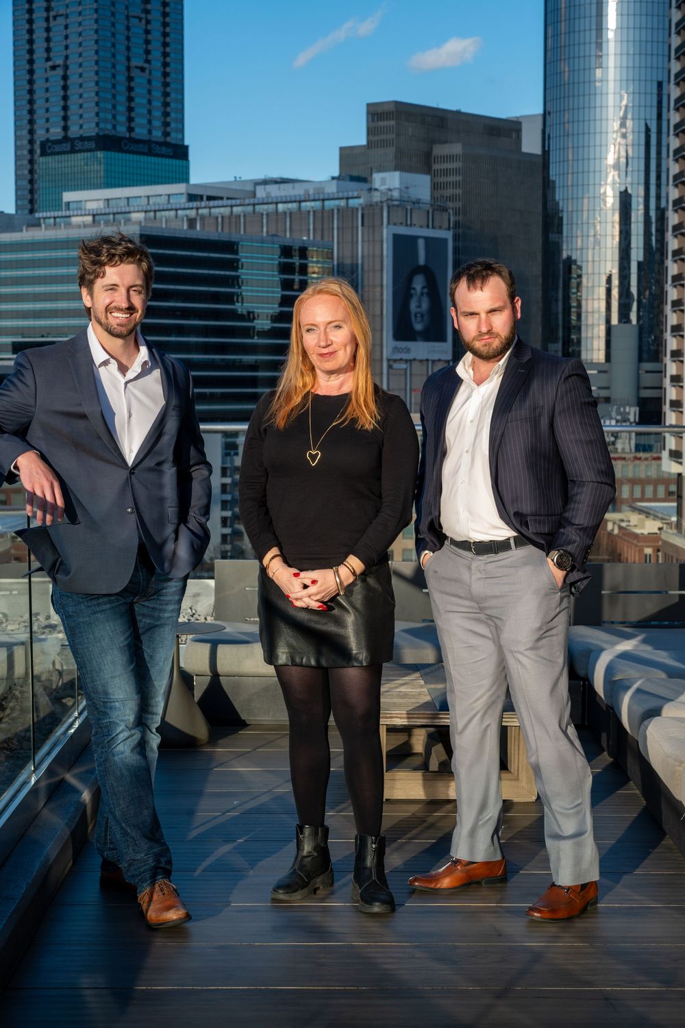 Group of professionals posing on an urban rooftop with modern skyscrapers in the background during blue hour.