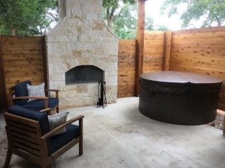 Stone patio with wooden outdoor furniture and rustic stone walls creates a peaceful backyard seating area.