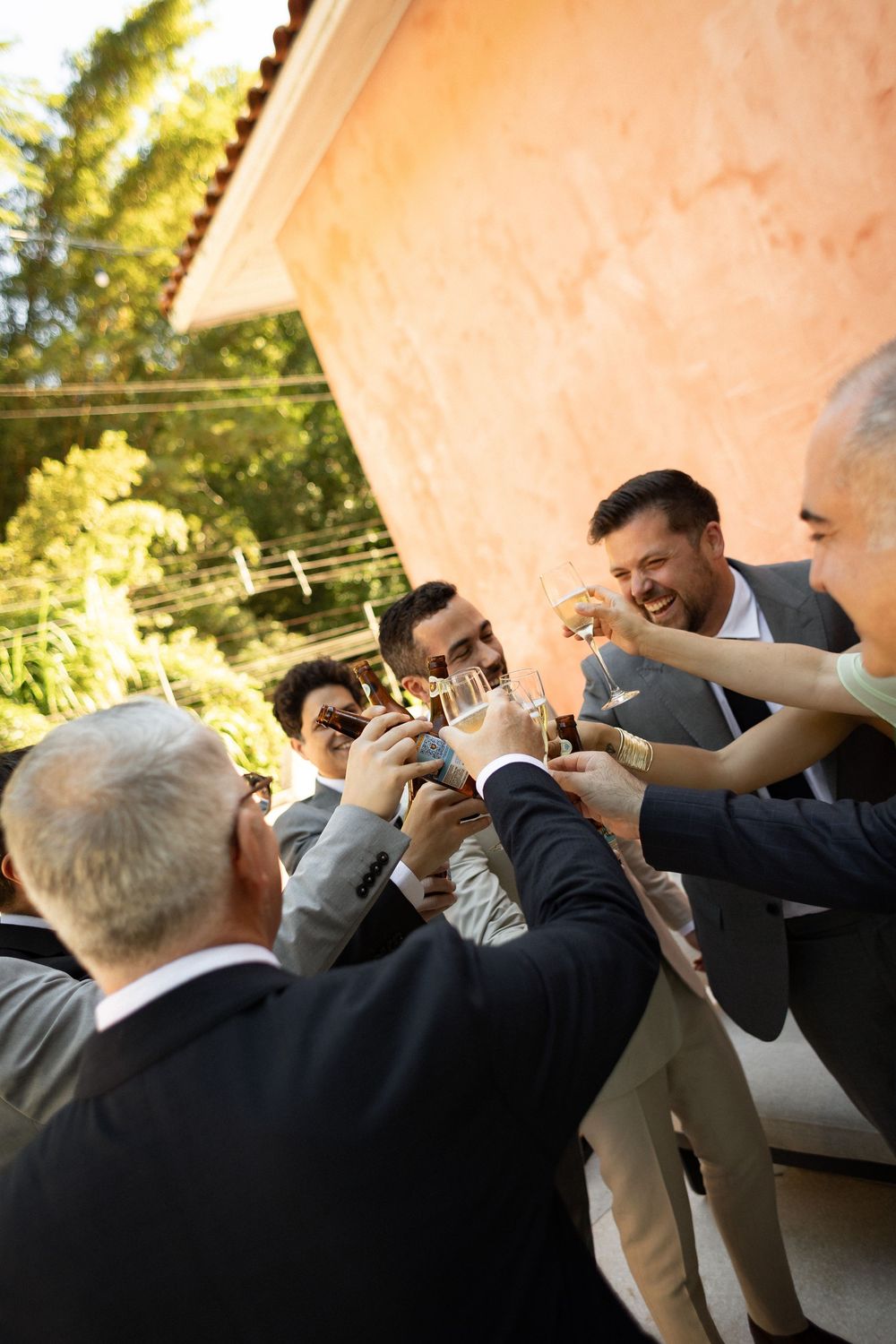 Wedding party members raising glasses in a celebratory toast outdoors.