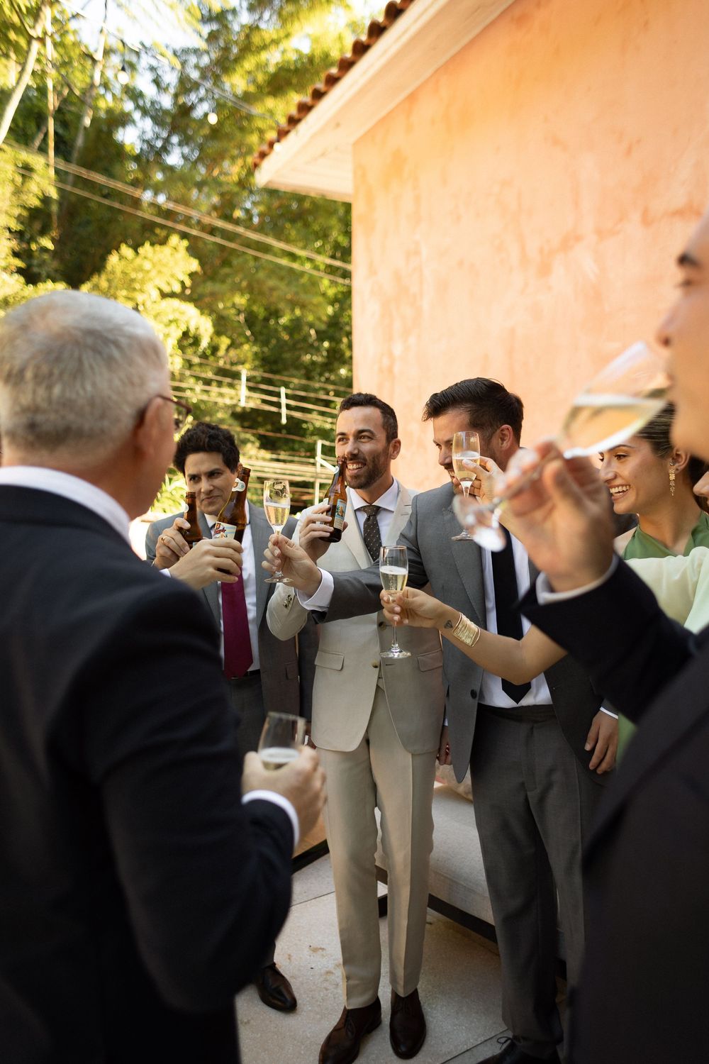 A group of well-dressed people share a celebratory toast on an outdoor terrace at sunset.