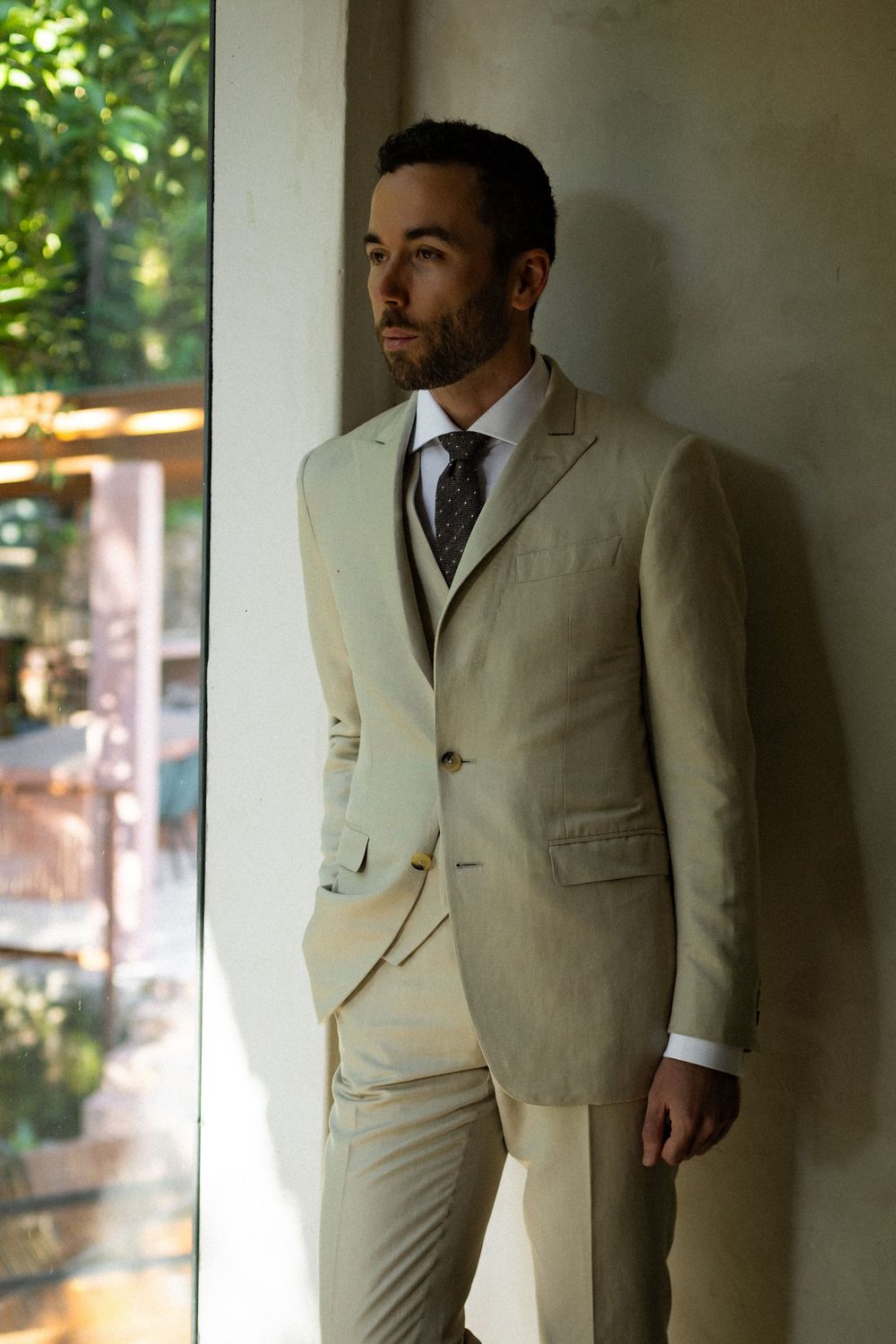 A formal cream-colored three-piece suit photographed in natural window lighting.