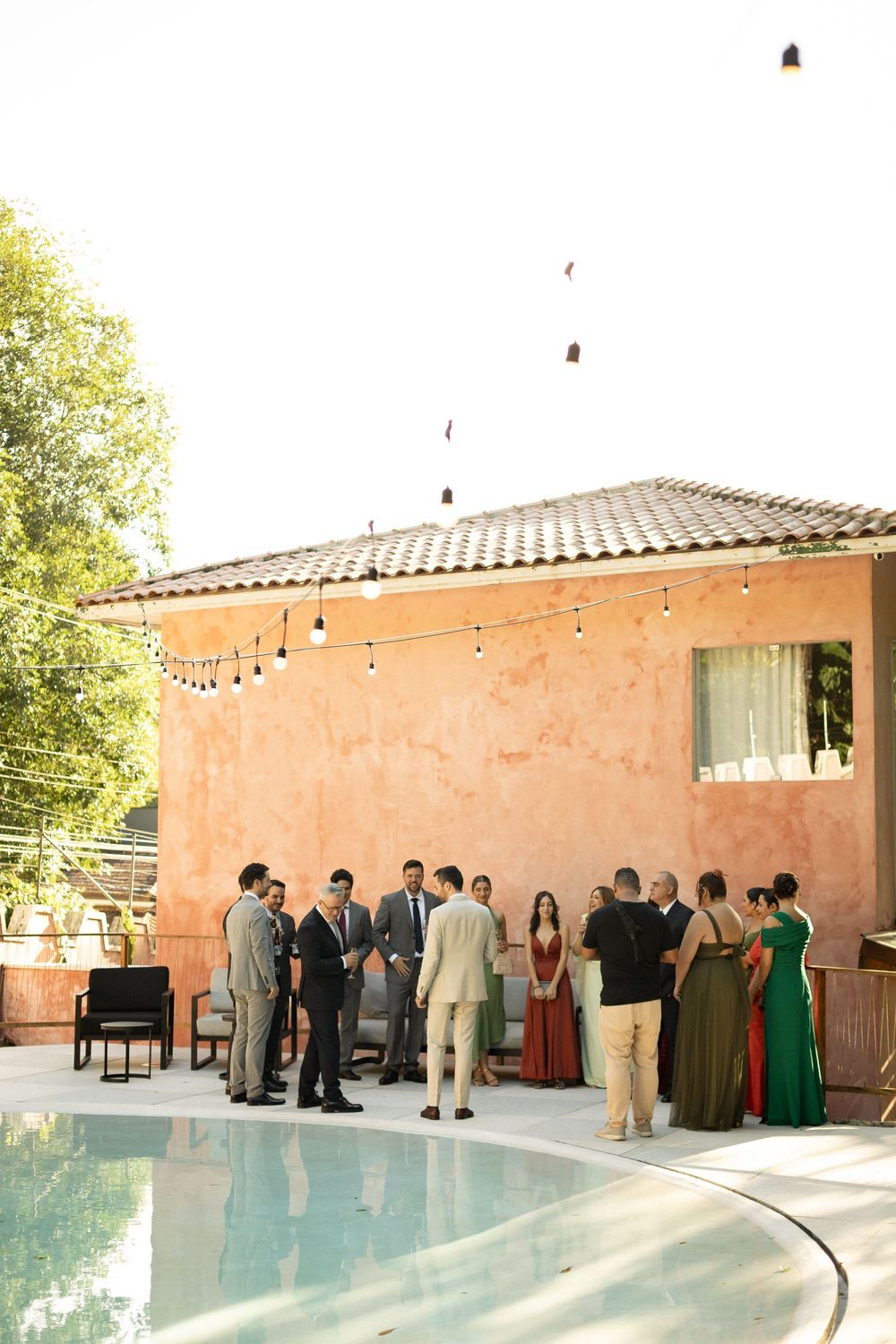 Guests gather around an outdoor swimming pool at a Mediterranean-style venue during an event.