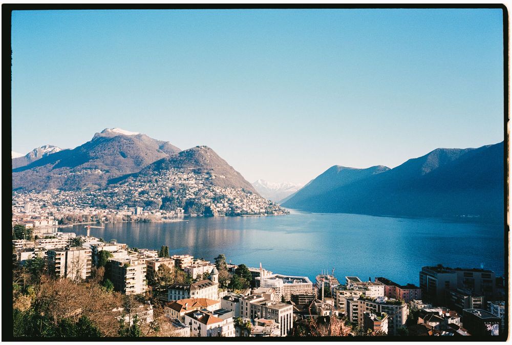 A panoramic view of a coastal city nestled between mountains and a blue bay with buildings along the waterfront.
