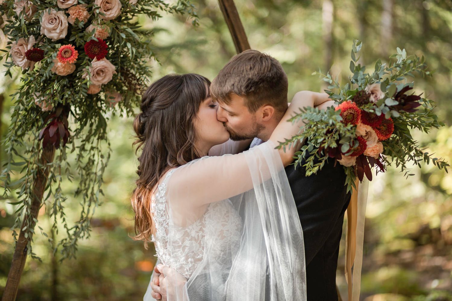 couple kisses under arbor at their mountain treehouse intimate wedding mont tremblant quebec canada