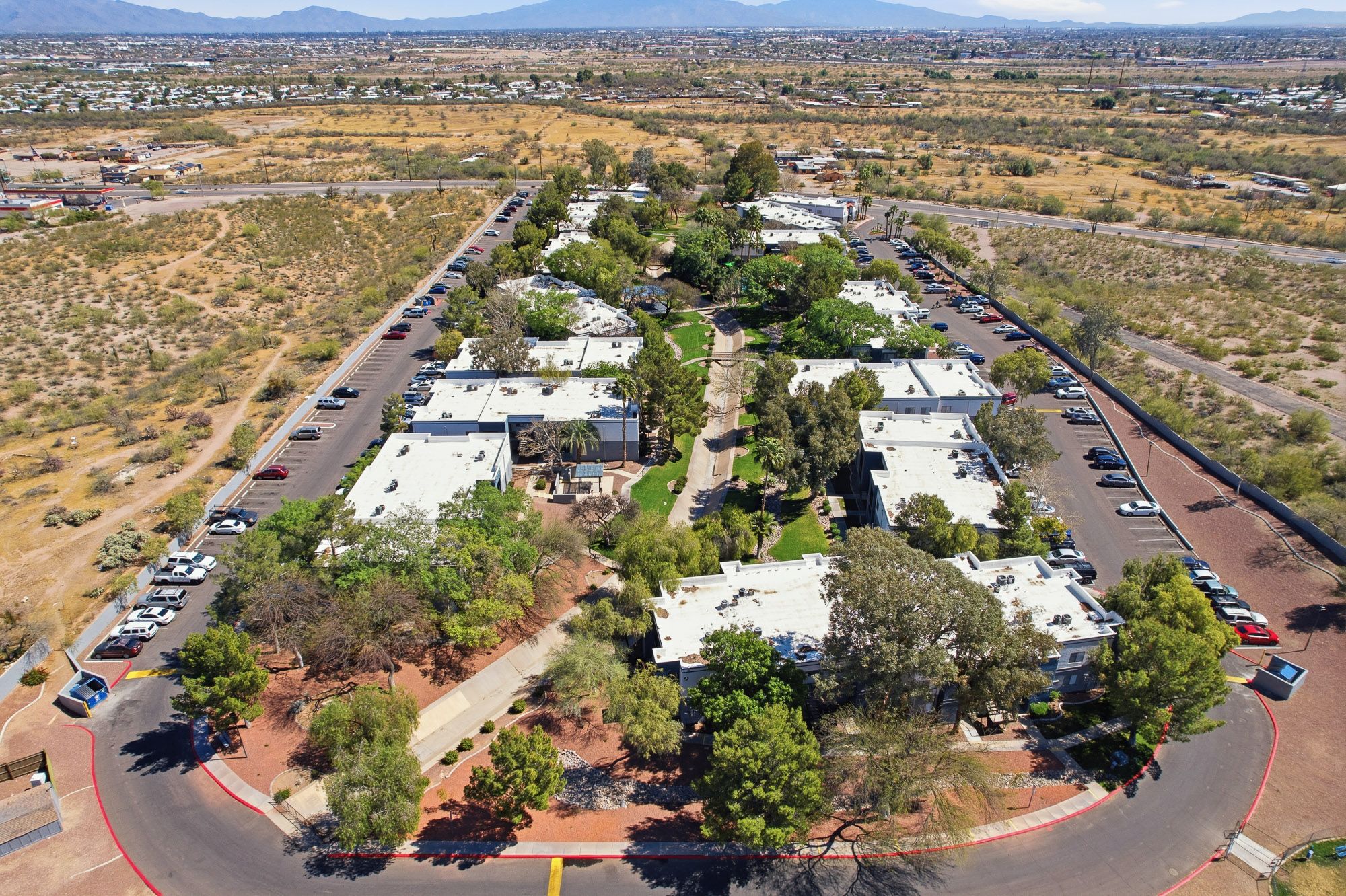 Aerial view of a residential apartment complex surrounded by desert landscape and mountains in Arizona.