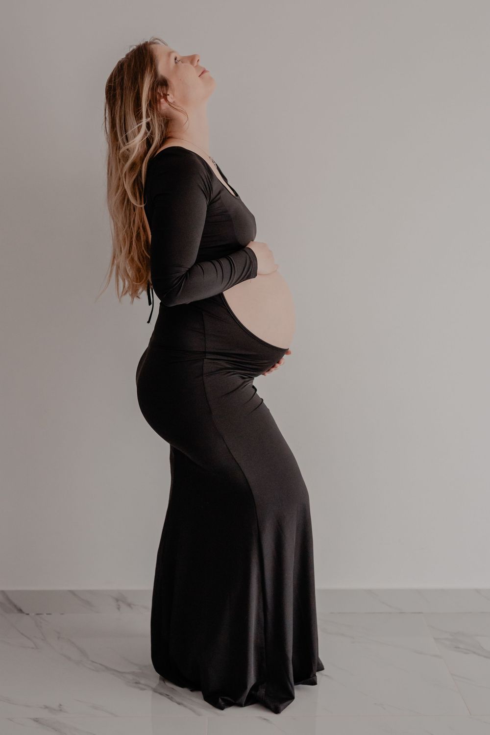 A series of maternity photos showing a woman in a flowing black dress posing against a white backdrop.